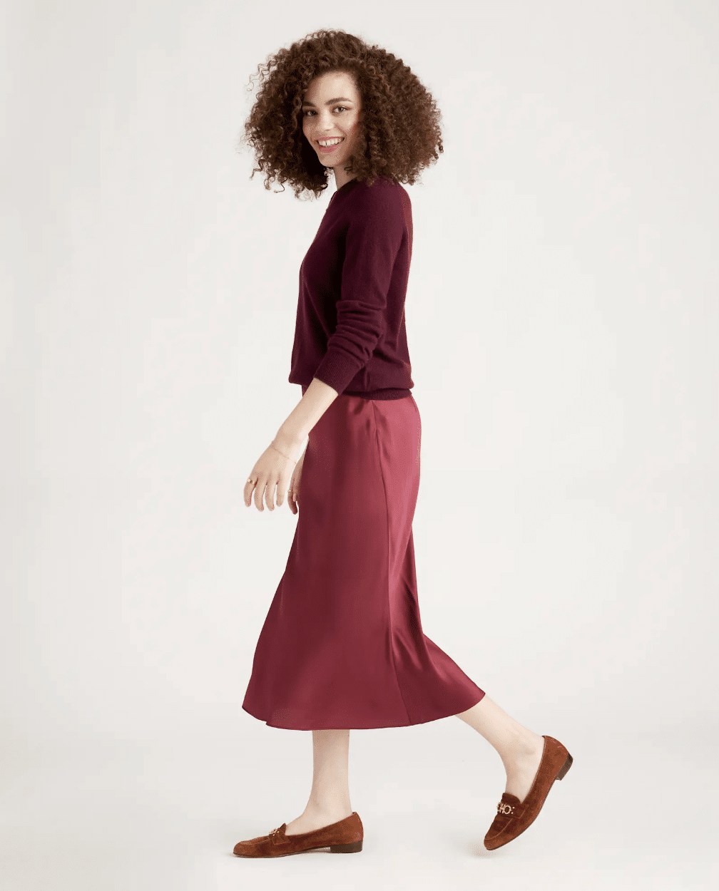 woman wearing a burgundy sweater with satin skirt classic holiday look outfit
