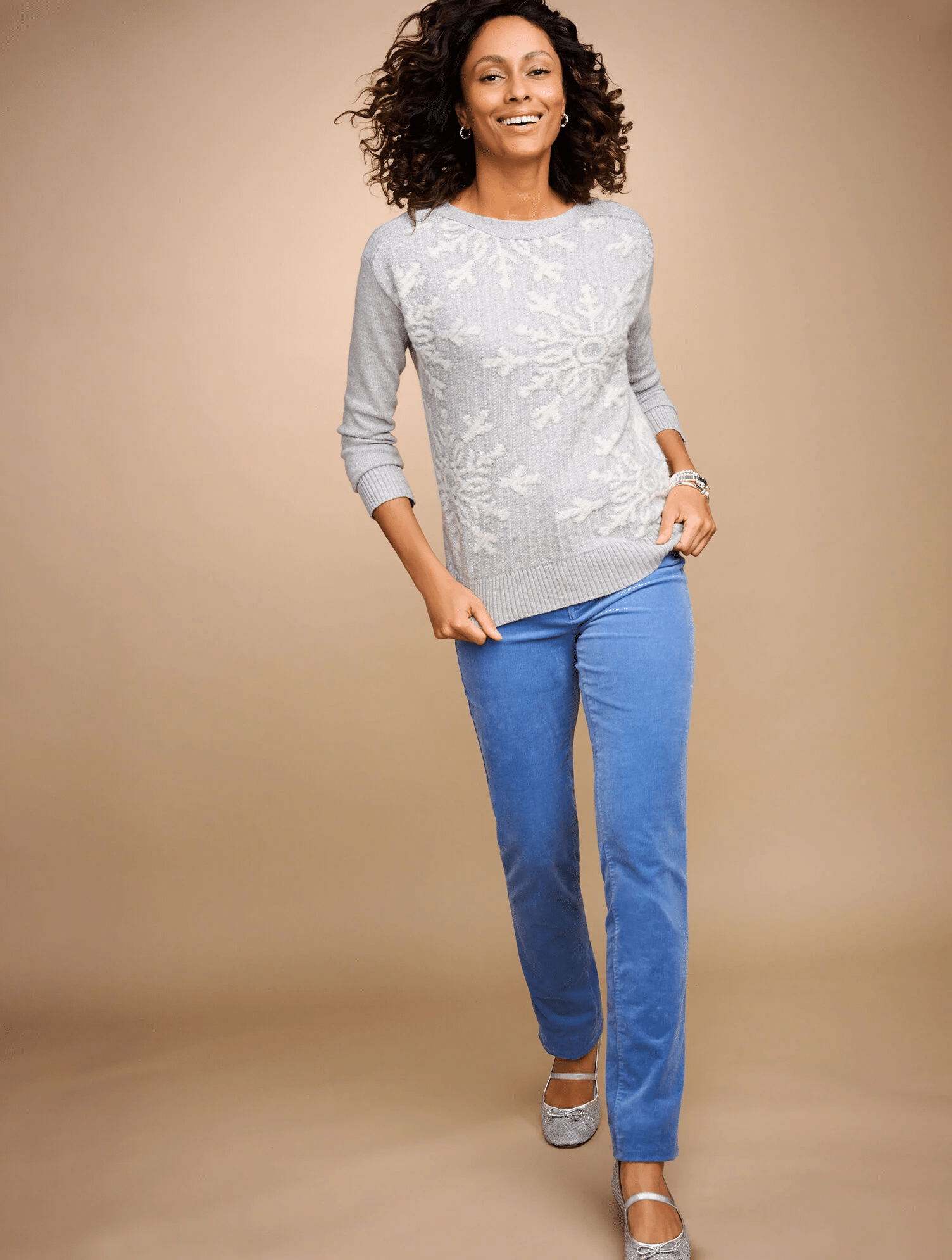 model wearing a snowflake sweater with blue pants and silver ballet flats