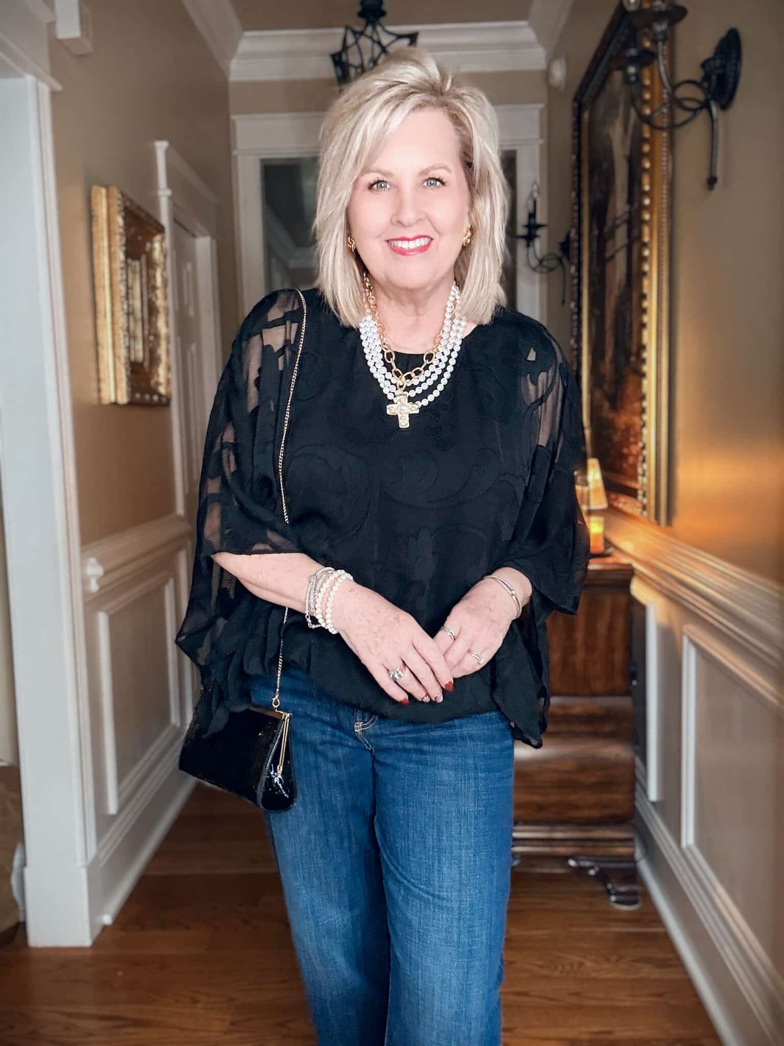 Tania in a black chiffon bubble hem top with a pearl necklace