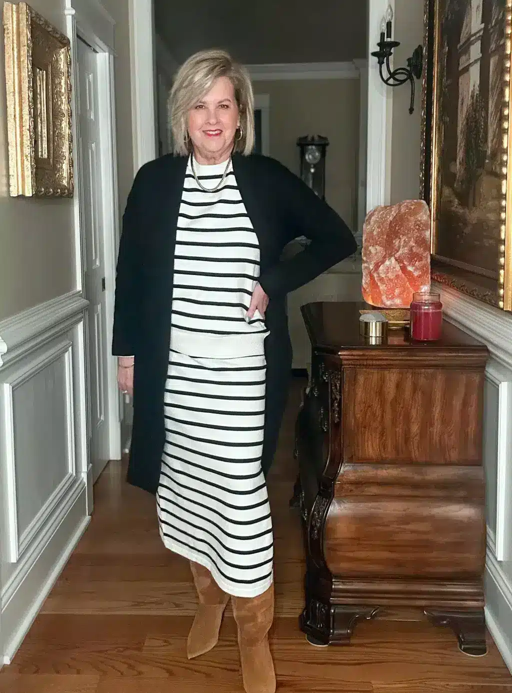 Tania wearing a striped black and white dress with brown boots.