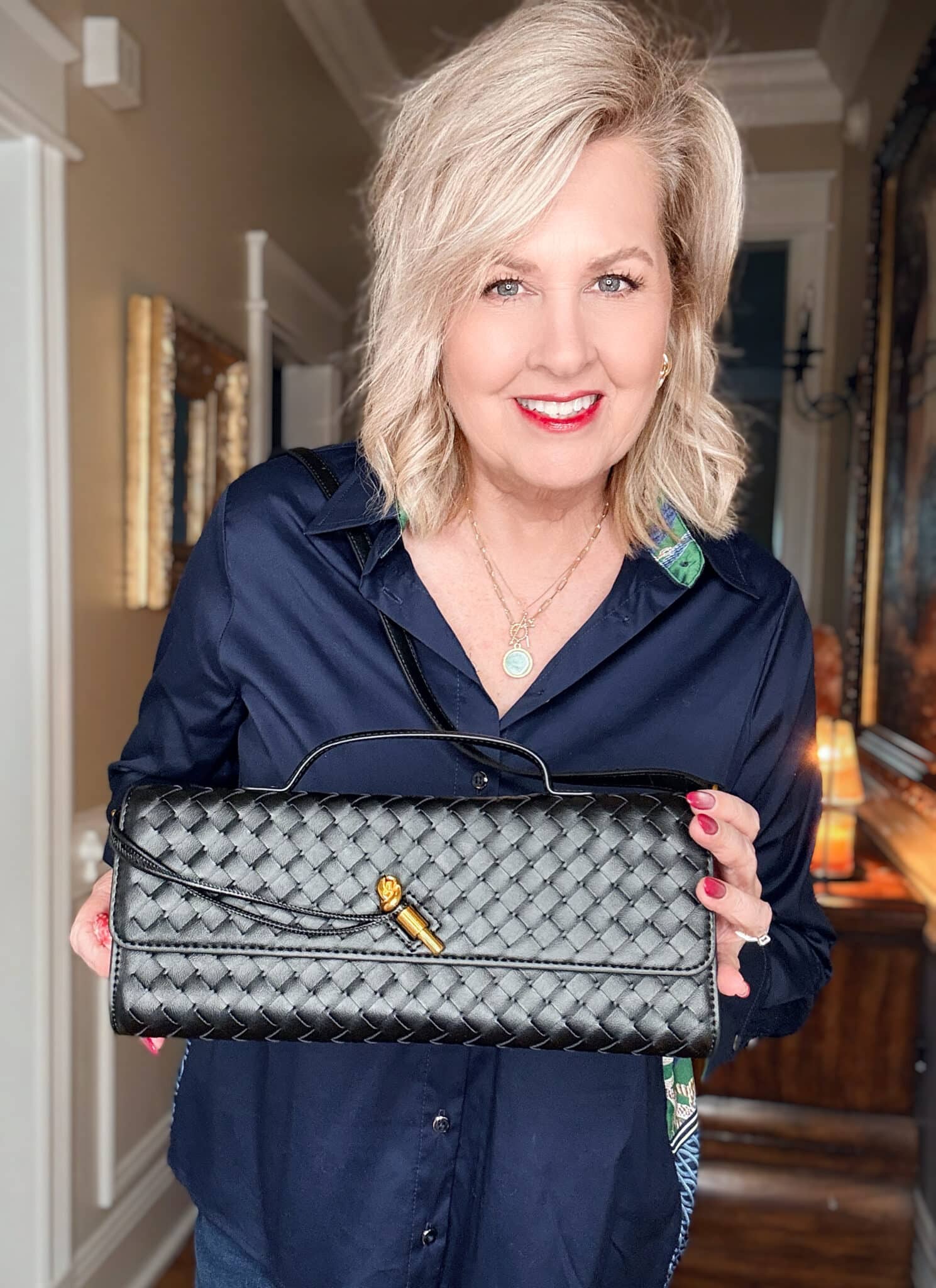 Tania wearing a navy top with a black woven clutch