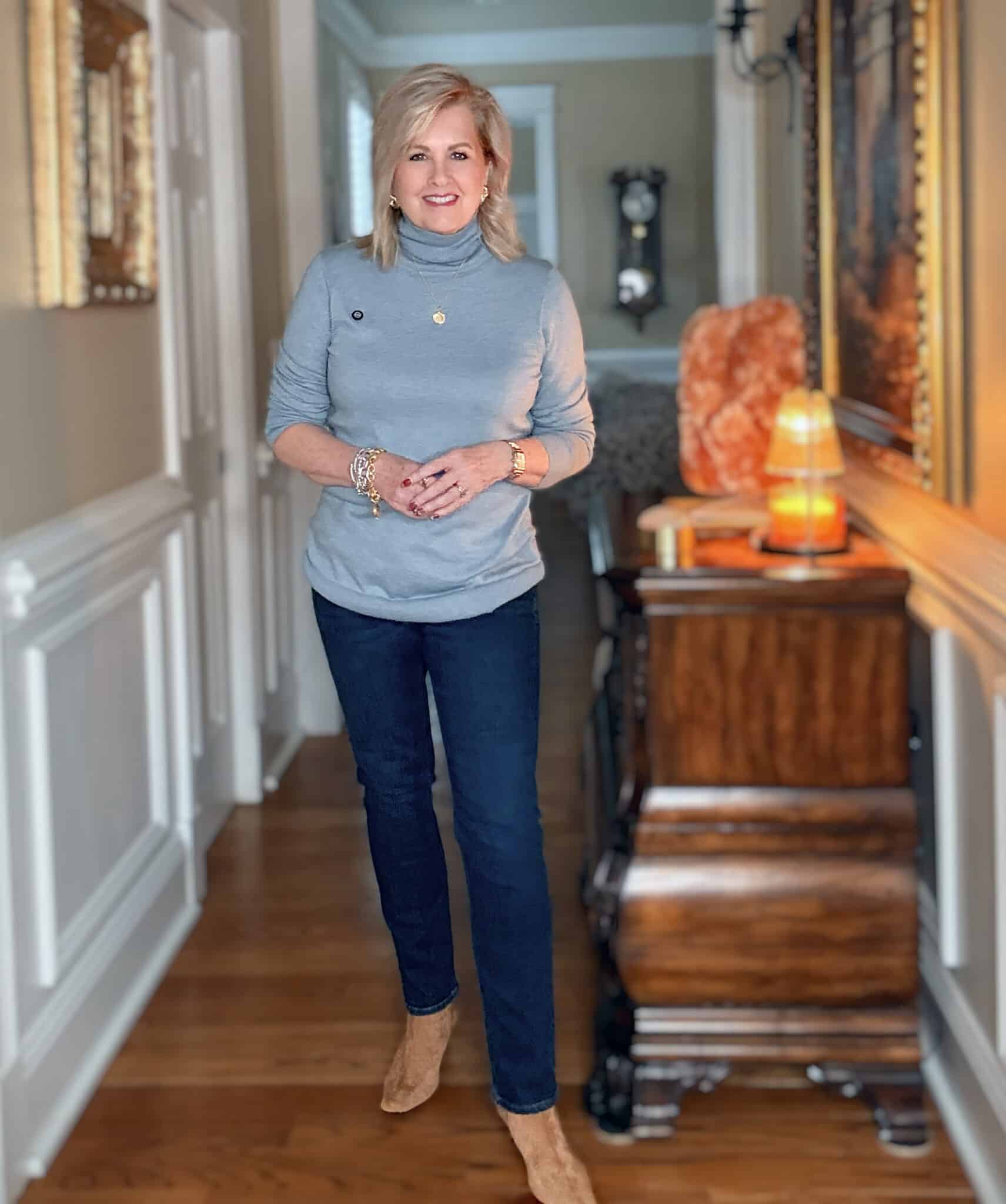 Tania wearing a blue turtleneck sweater with dark wash jeans from Quince