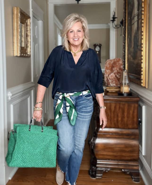 Tania wearing a navy shirt with jeans and a bright green tote
