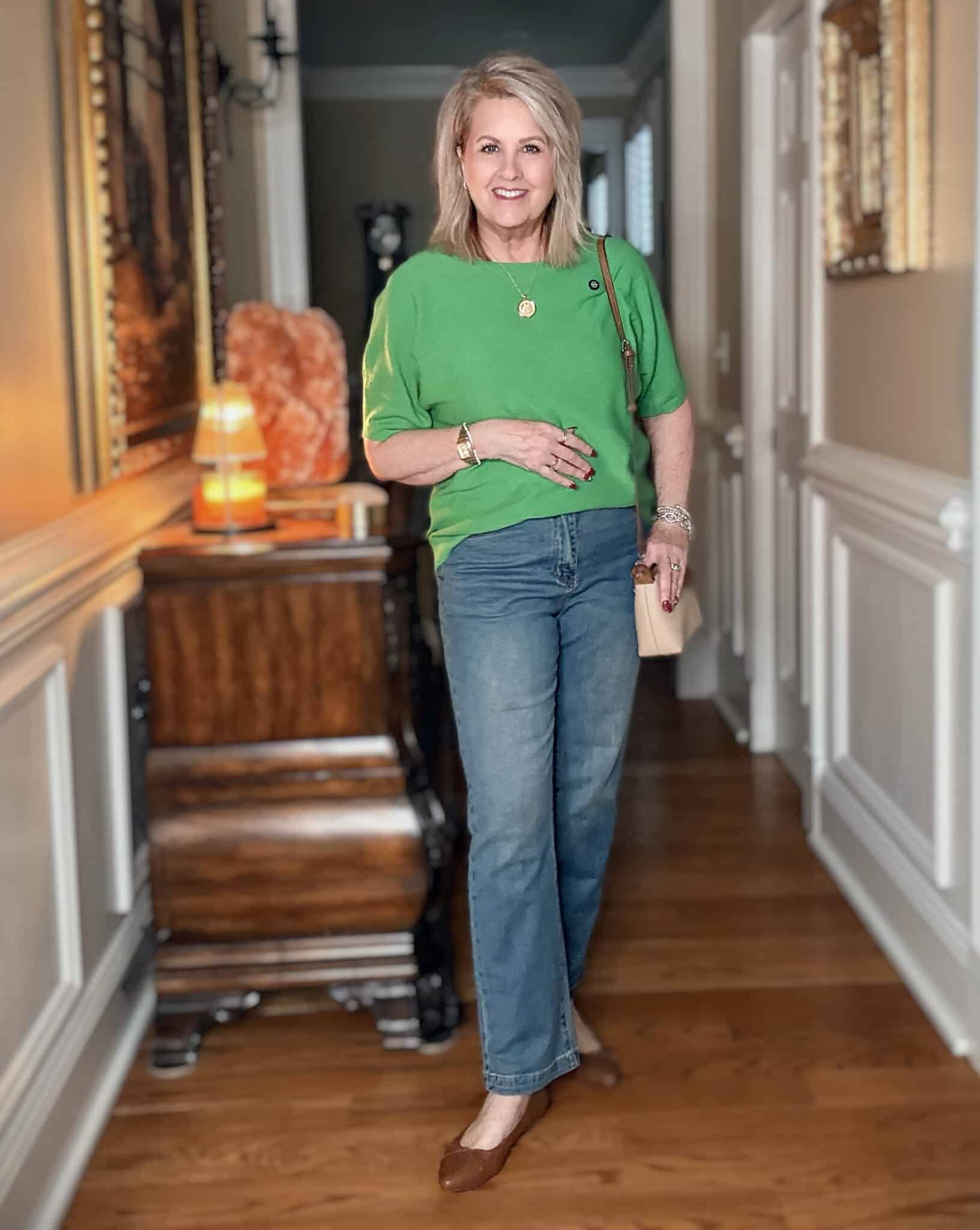 Tania wearing a green sweater with jeans and a small crossbody bag