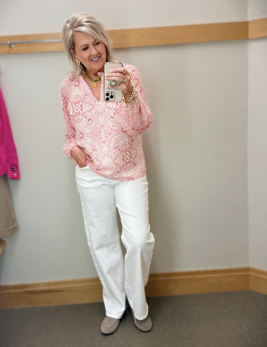woman over 50 wearing pink paisley top with white jeans feminine spring outfit