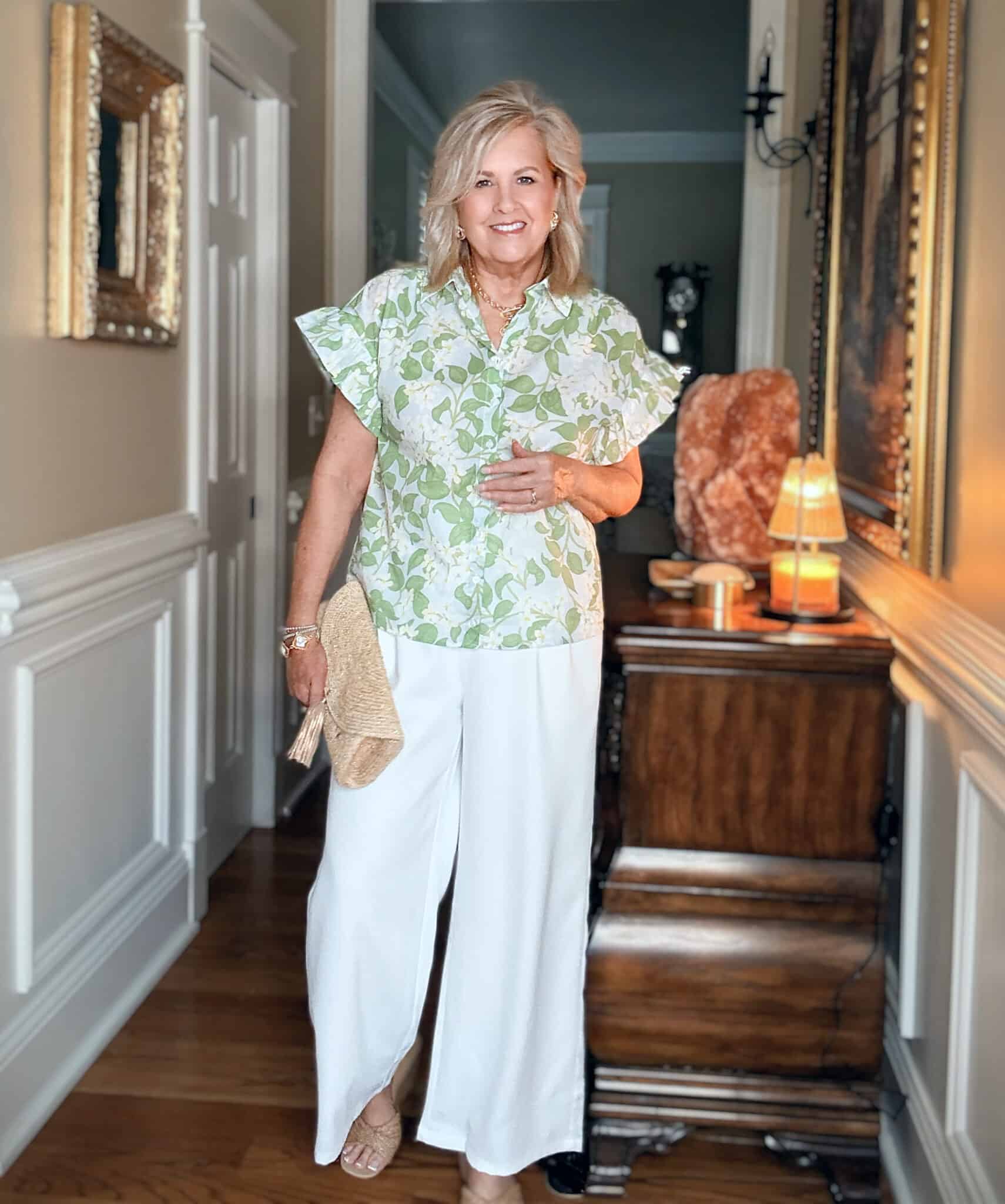 Tania Stephens demonstrating the "light and airy" approach to style over 50. She wears white wide-leg pants and a green floral top