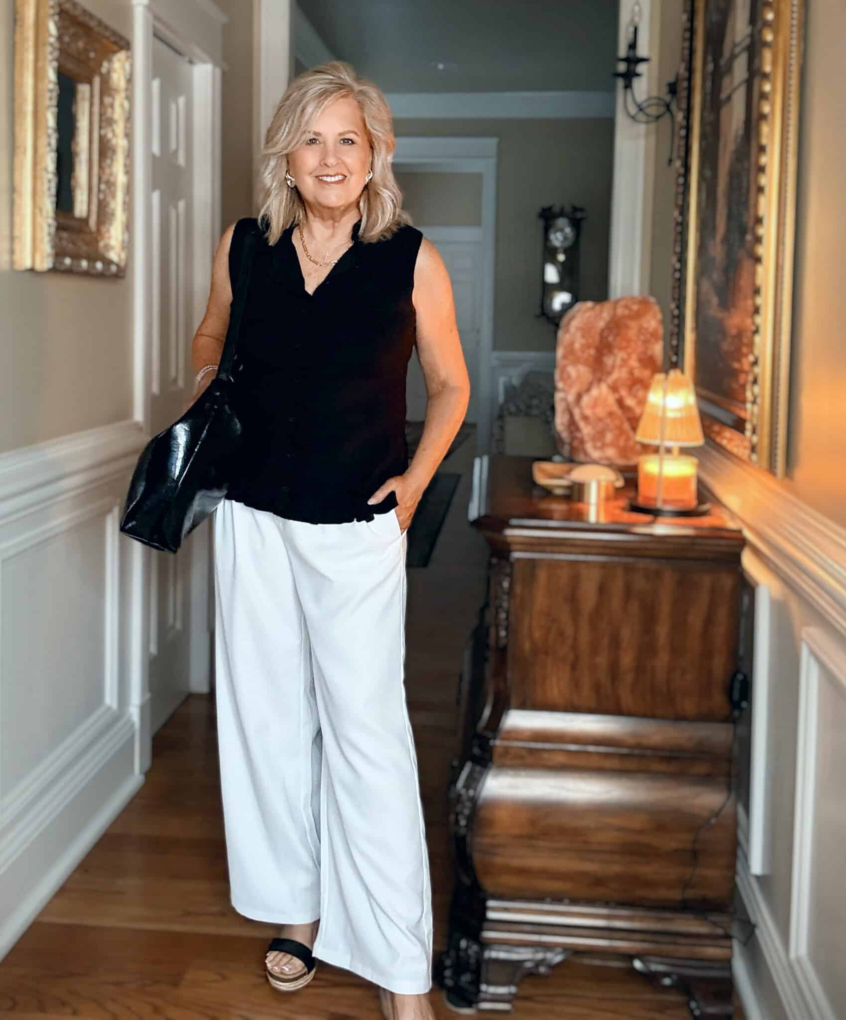 Style tips for women over 50, showing Tania Stephens in white wide-leg pants and a black sleeveless top