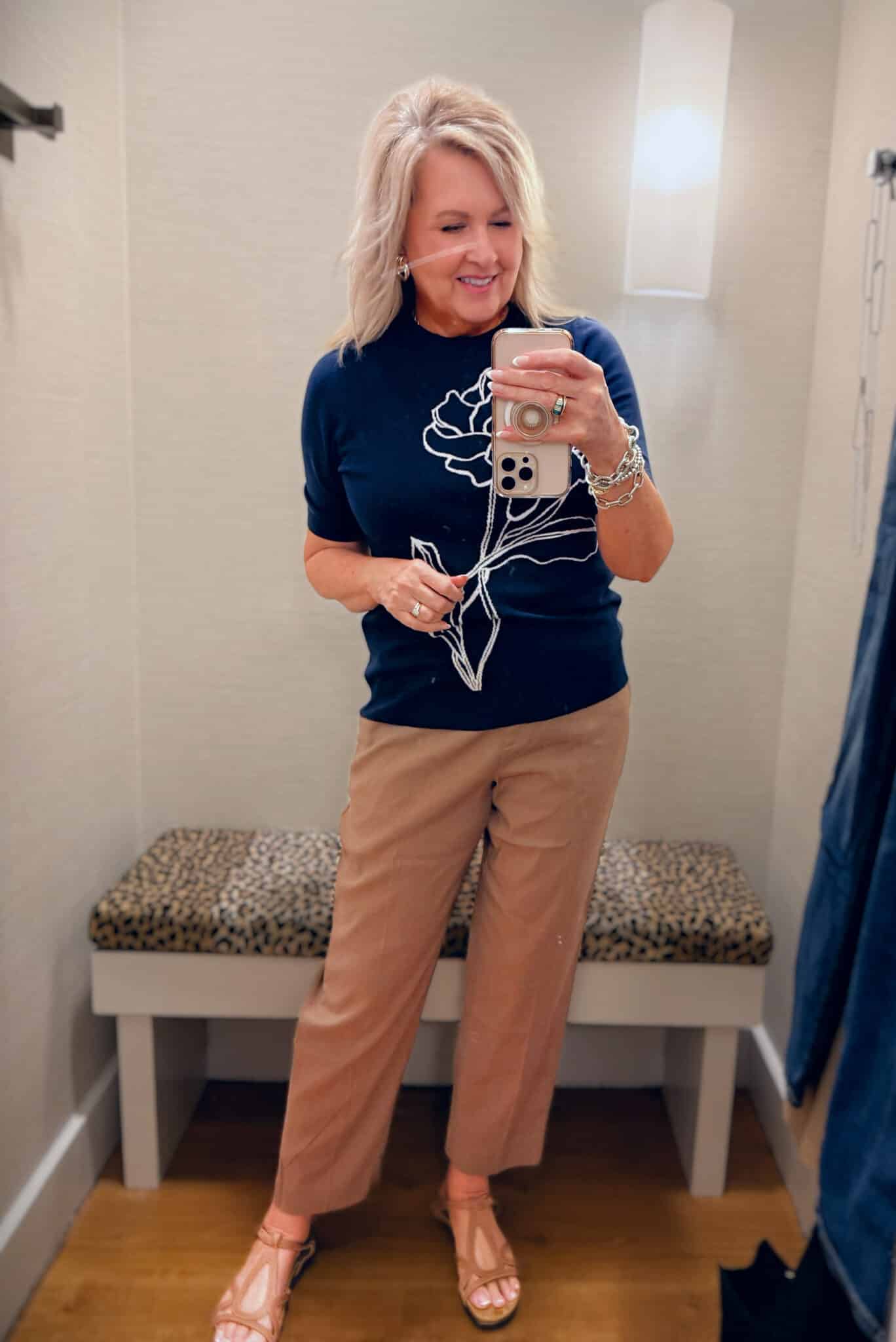 Tania wearing a Chico's navy sweater with a embroidered flower and brown pants
