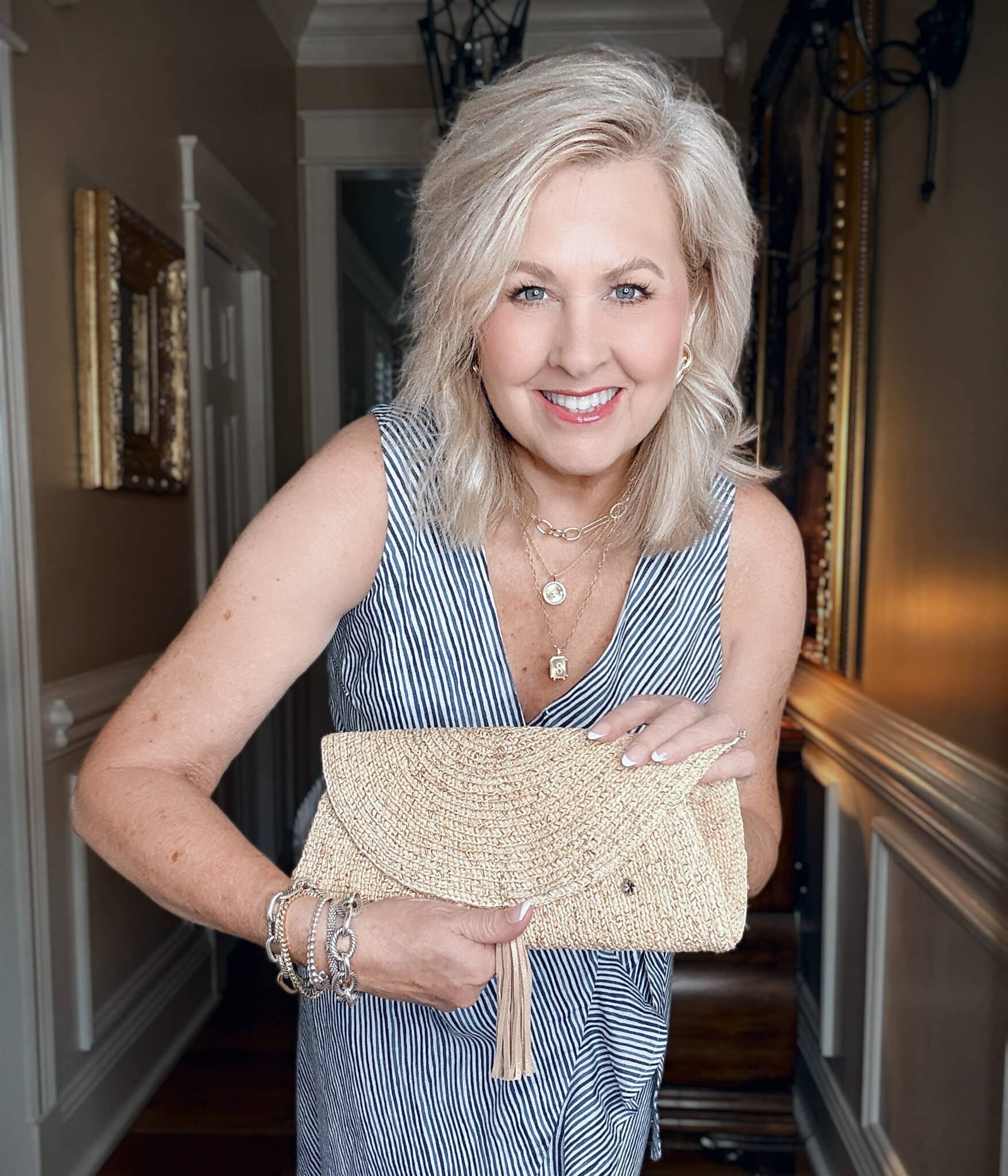 Tania wearing a Tommy Bahama striped dress and holding a straw clutch