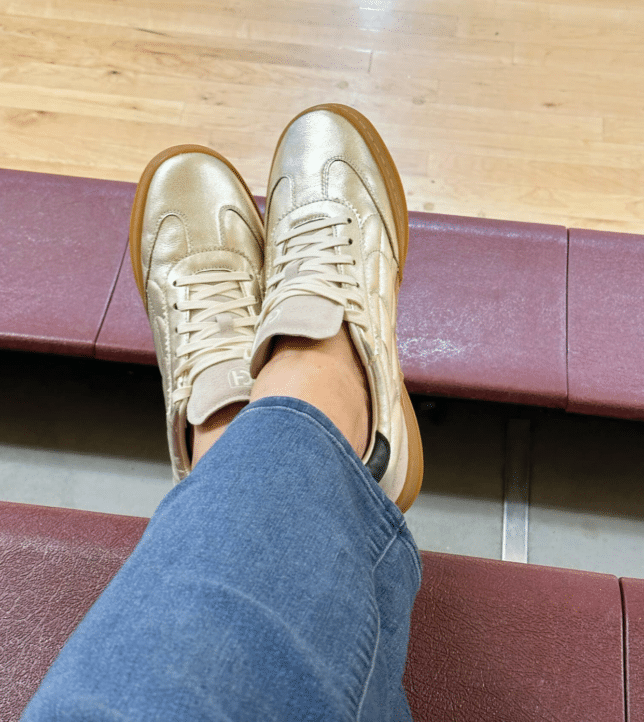 Tania wearing gold sneakers at a ballgame