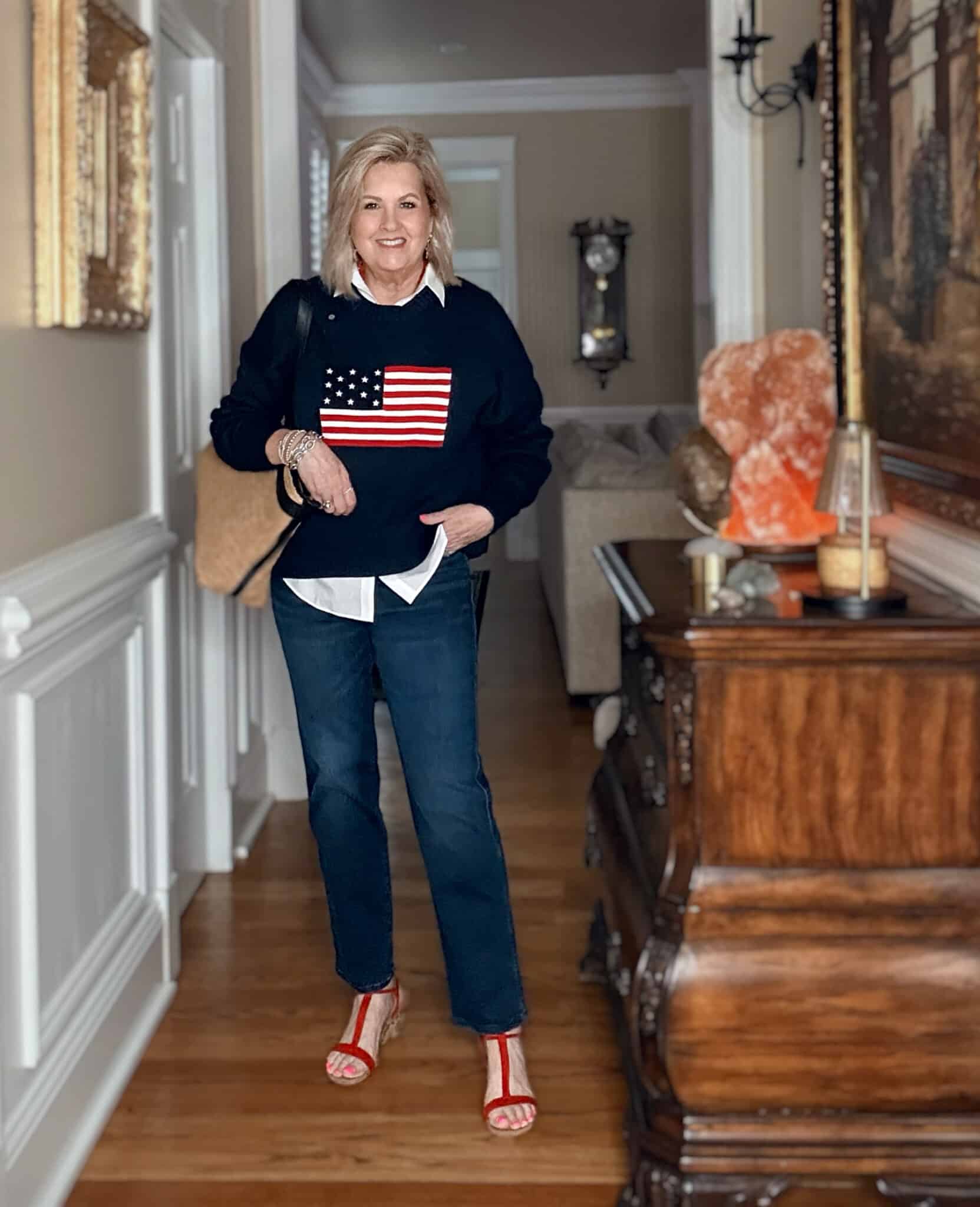 Tania wearing a white shirt with a navy American flag sweater and dark wash jeans