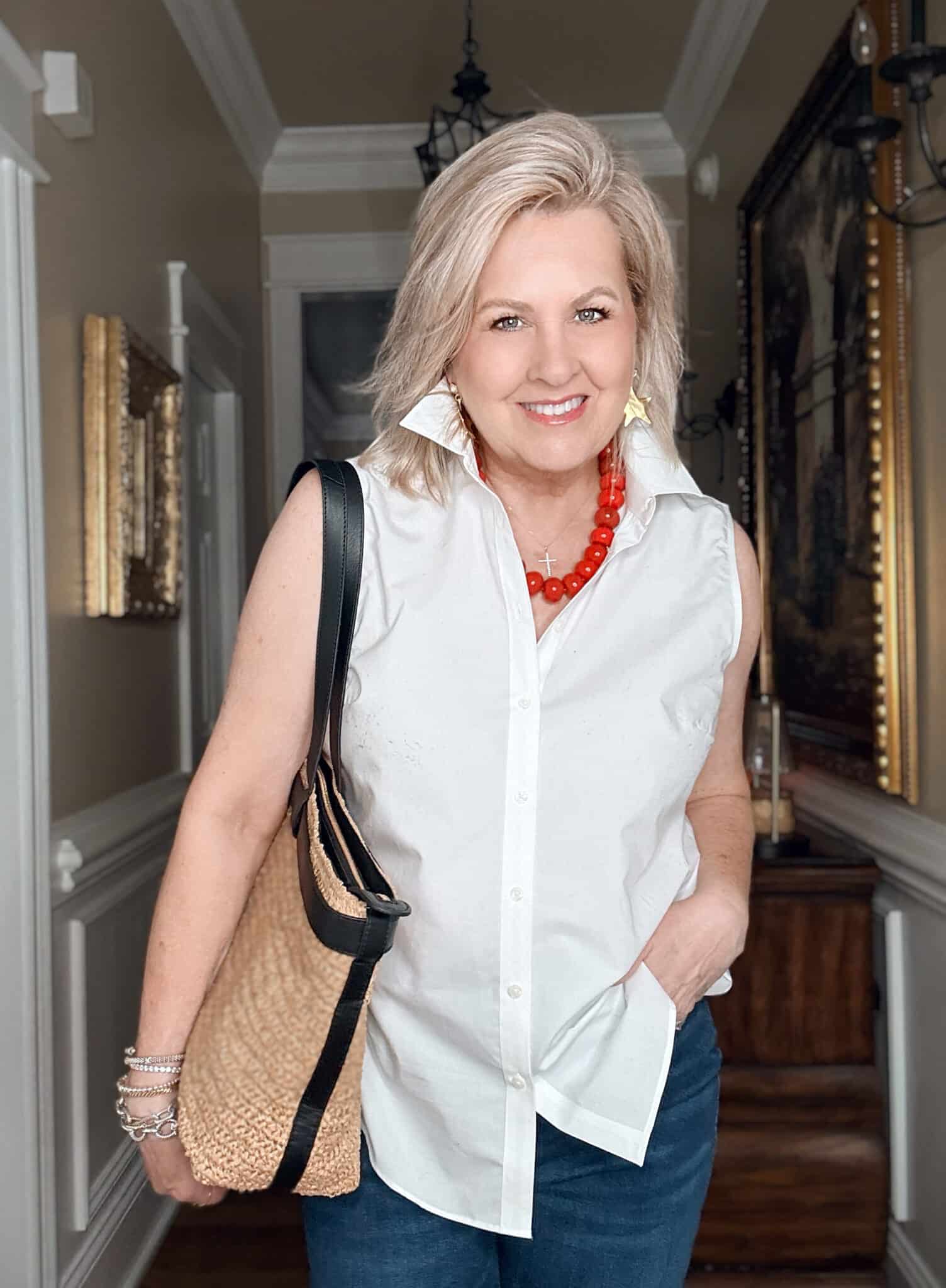 Tania wearing a sleeveless white shirt with a large red necklace