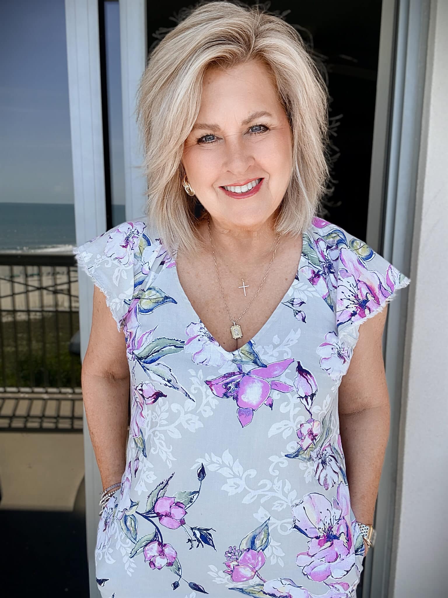 Tania wearing a Tommy Bahama floral sheath dress at the beach with gold necklaces