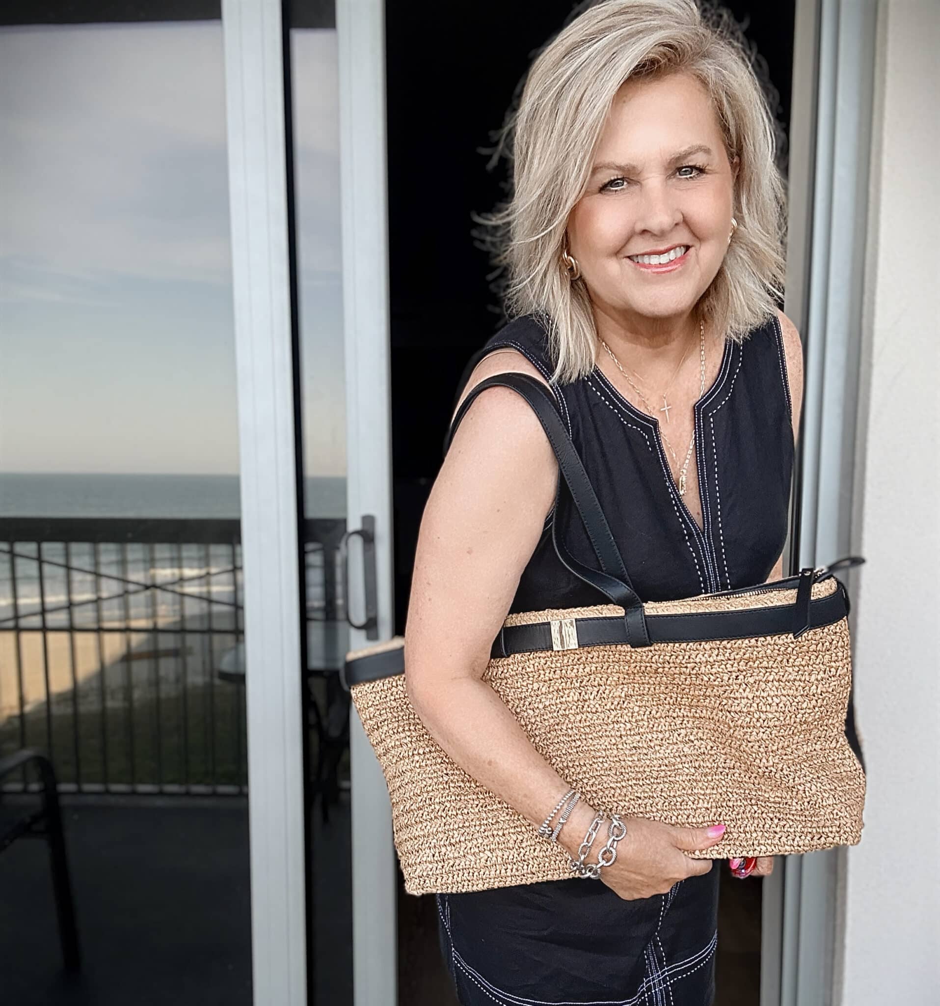 Tania wearing a Tommy Bahama black sheath dress with a raffia bag