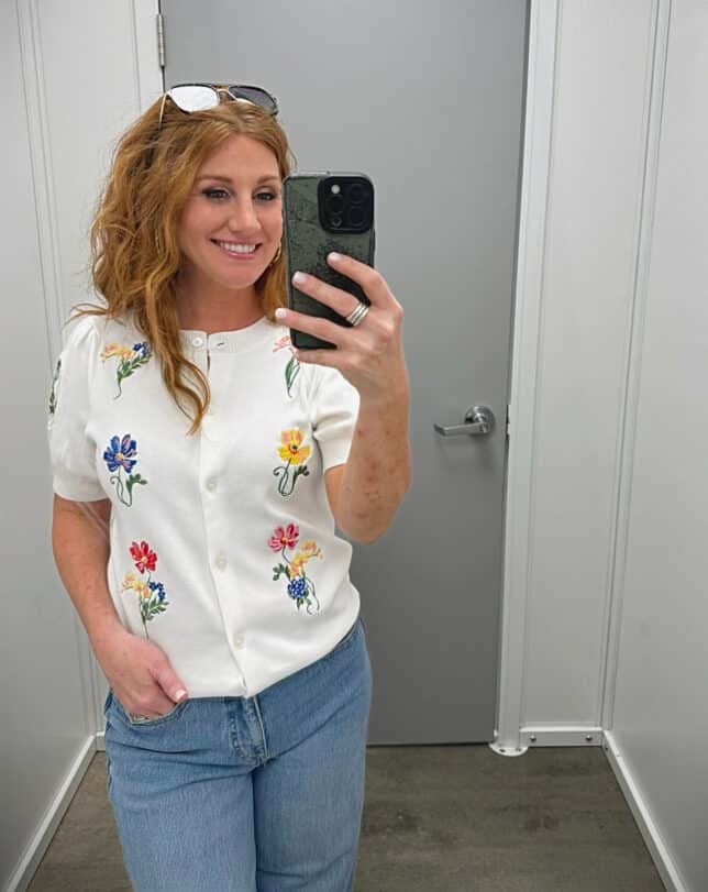 Stephanie is wearing a white floral sweater with wide leg jeans