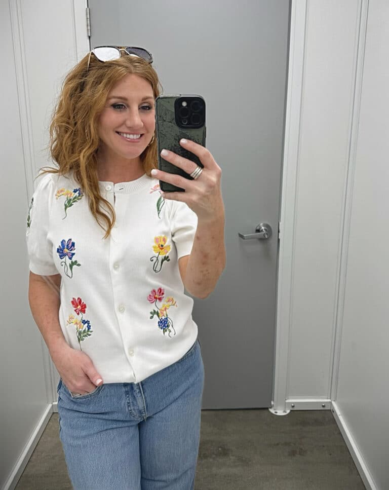 Stephanie is wearing a white floral sweater with wide leg jeans
