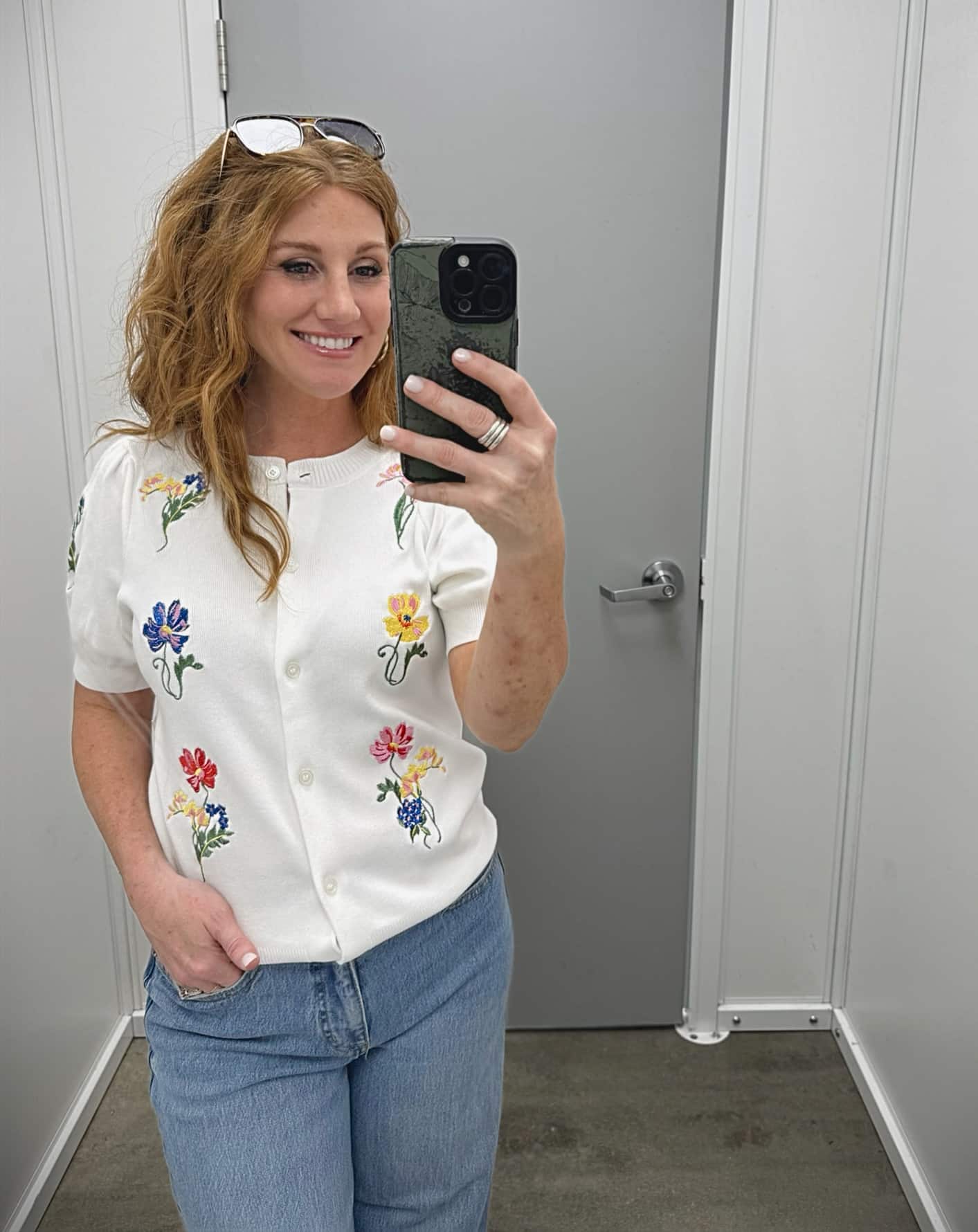 Stephanie is wearing a white floral sweater with wide leg jeans
