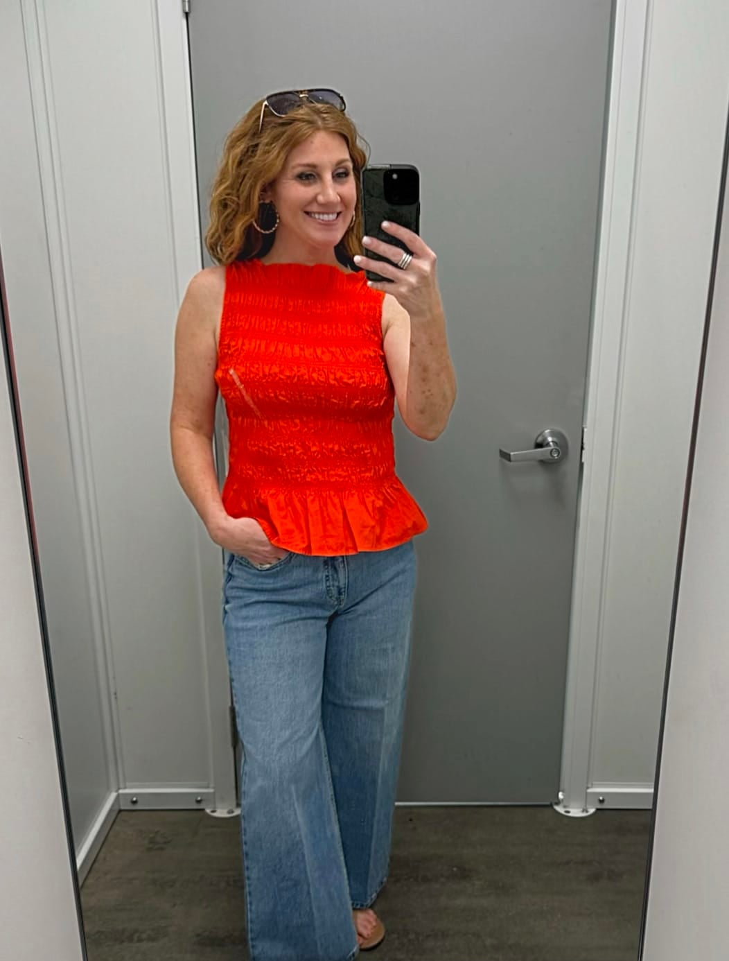 Stephanie is wearing a red sleeveless top with wide leg jeans