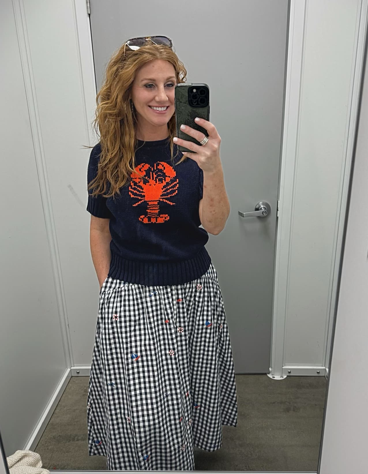 Stephanie is wearing a navy sweater with a red lobster with a gingham skirt