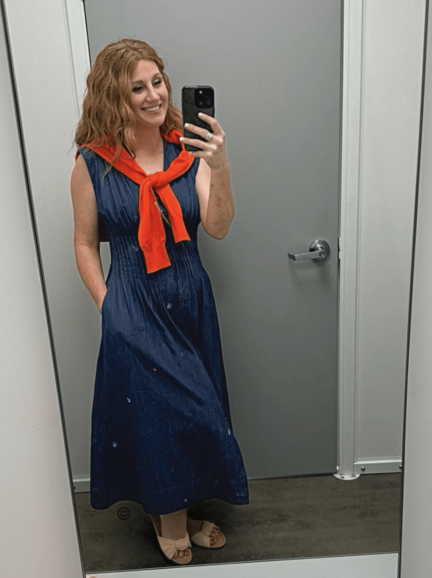 Stephanie is wearing a navy dress with a red sweater