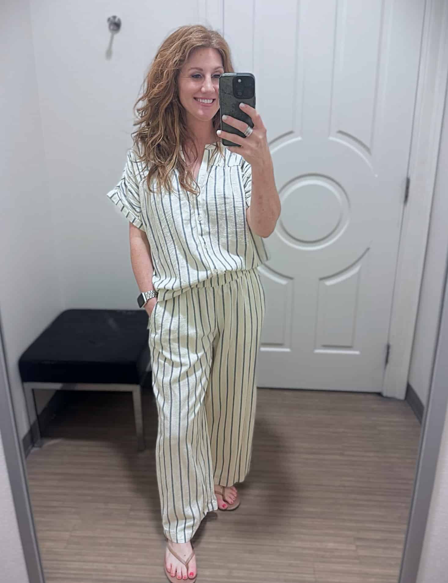 Stephanie wearing a striped shirred shoulder top and matching striped mid-rise pants from Belk with neutral thong sandals.