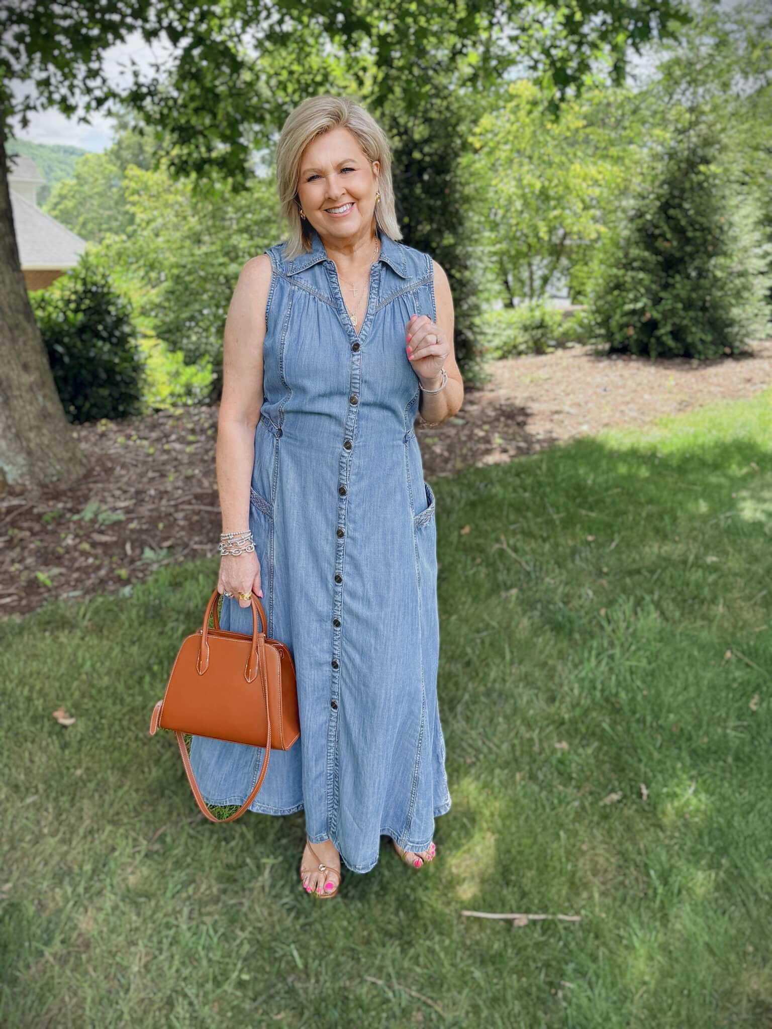 Tania wearing a sleeveless chambray v-neck midi dress with flat sandals and brown bowler bag