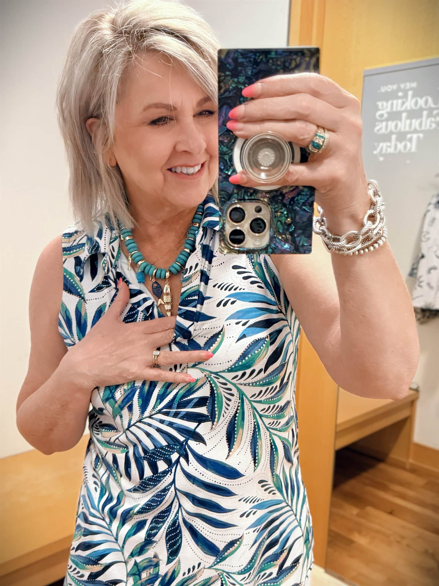 Tania wearing a sleeveless top on a palm print with a large stone/fish necklace from Chicos