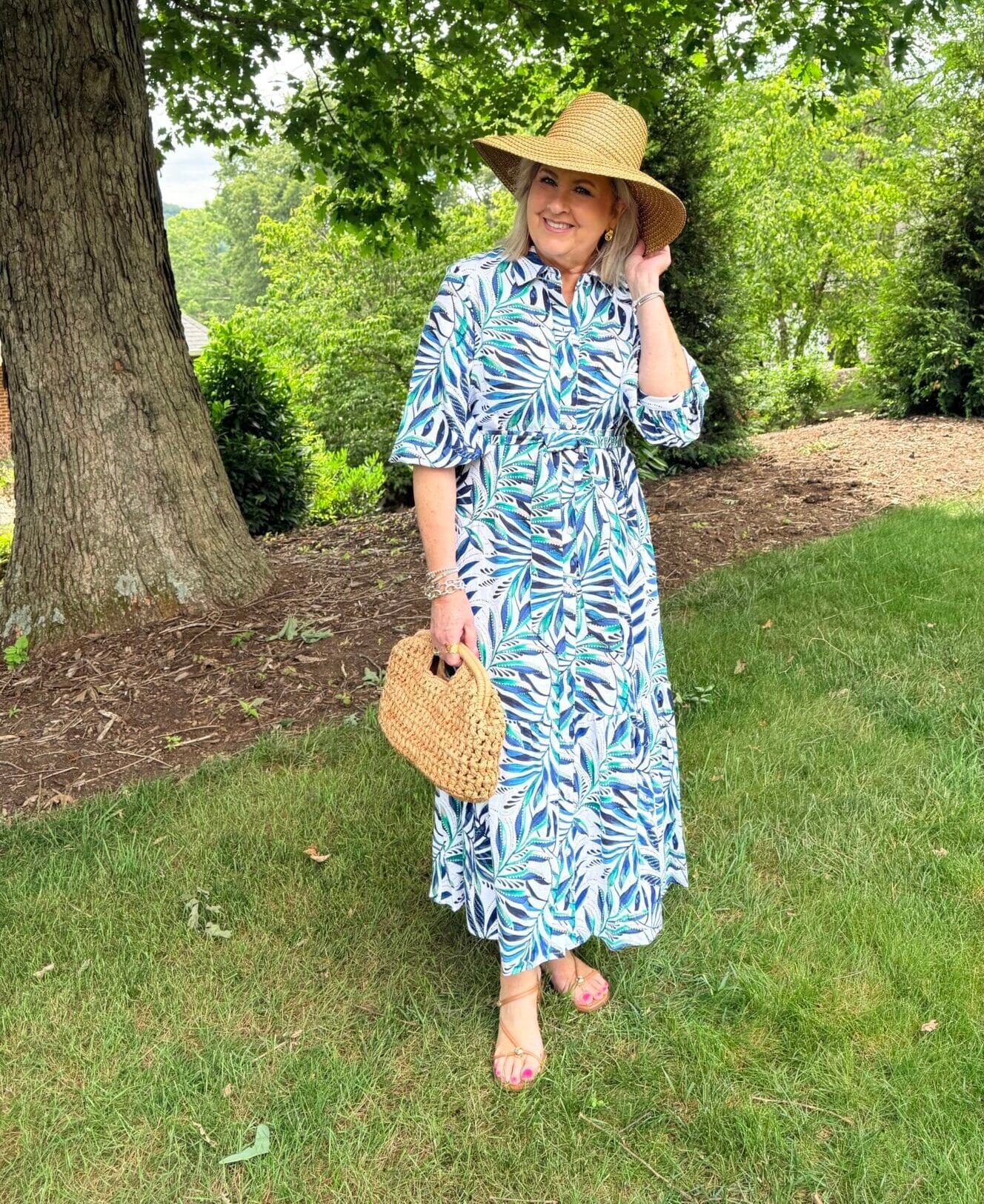 Tania wearing a straw sunhat with a palm print dress from Chico's