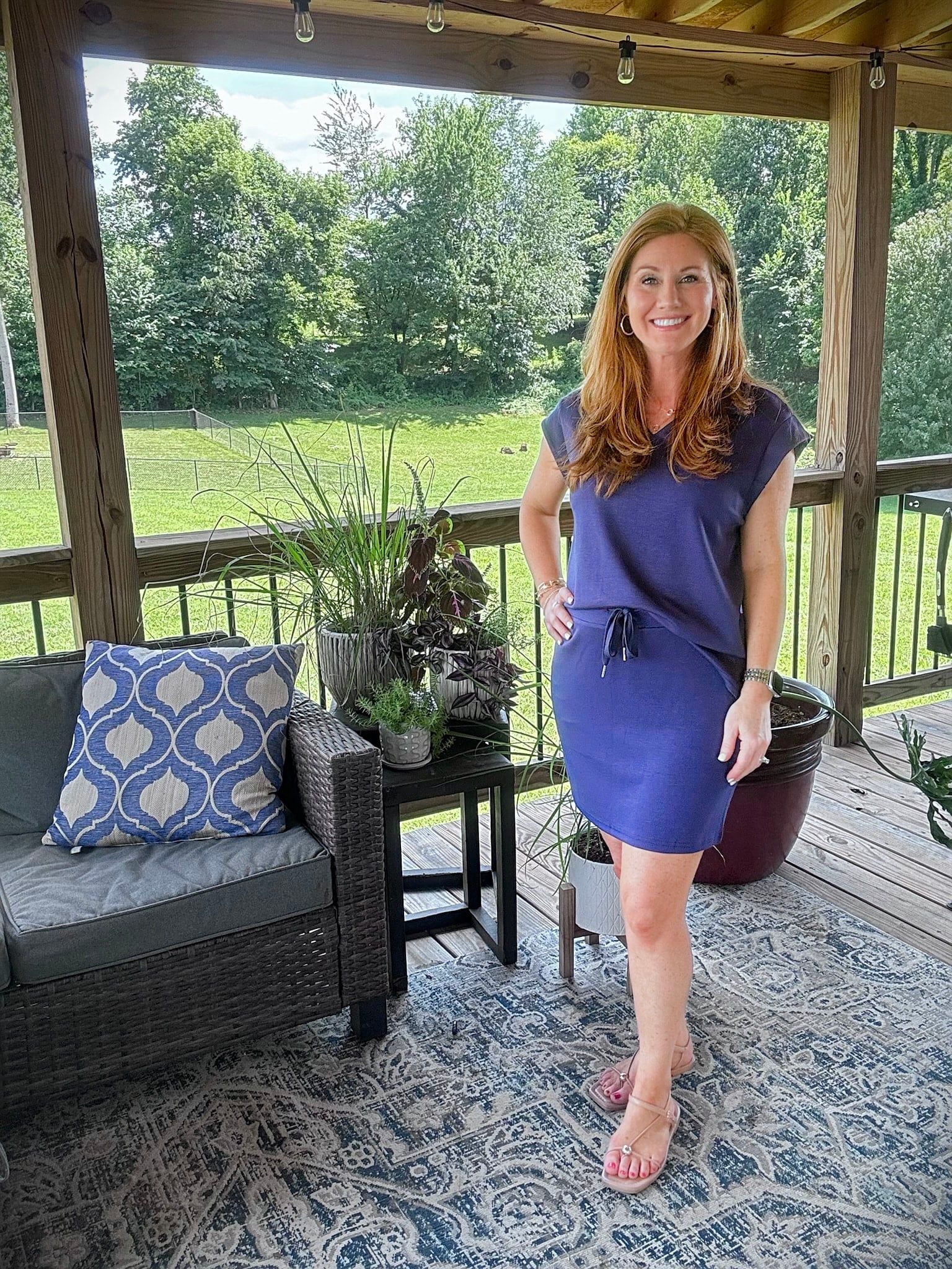 Petite woman wearing a navy two-piece skirt set with flat strappy sandals for summer