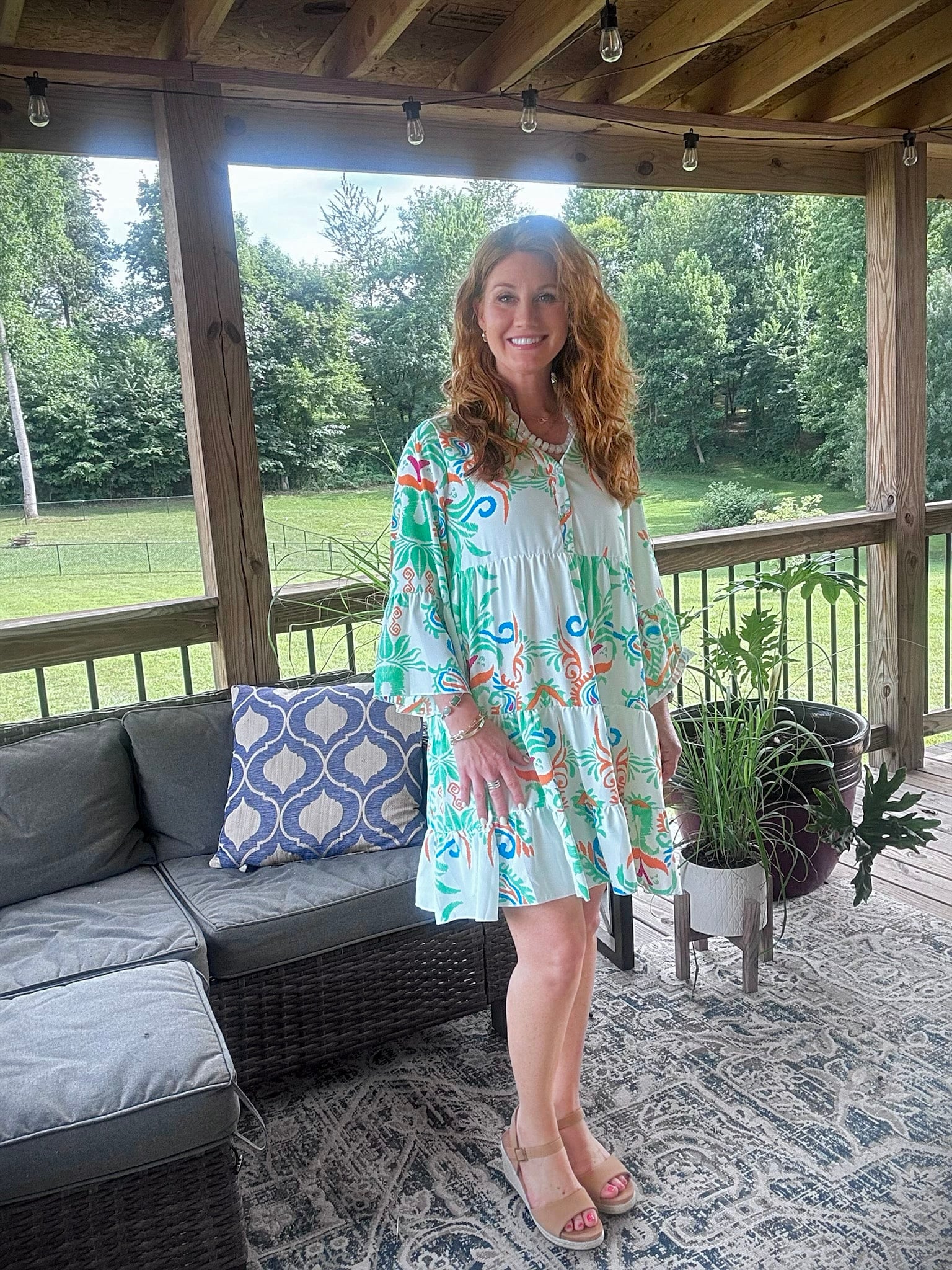 Petite woman wearing a colorful bohemian flowy mini dress with espadrille sandals