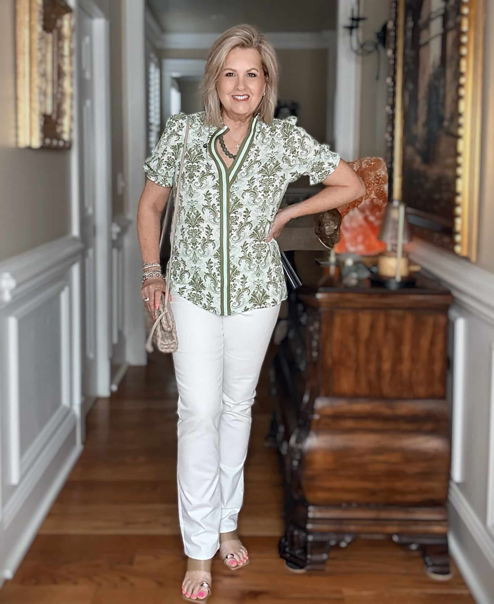 Woman over 50 wearing a green floral V-neck shirt with white straight jeans
