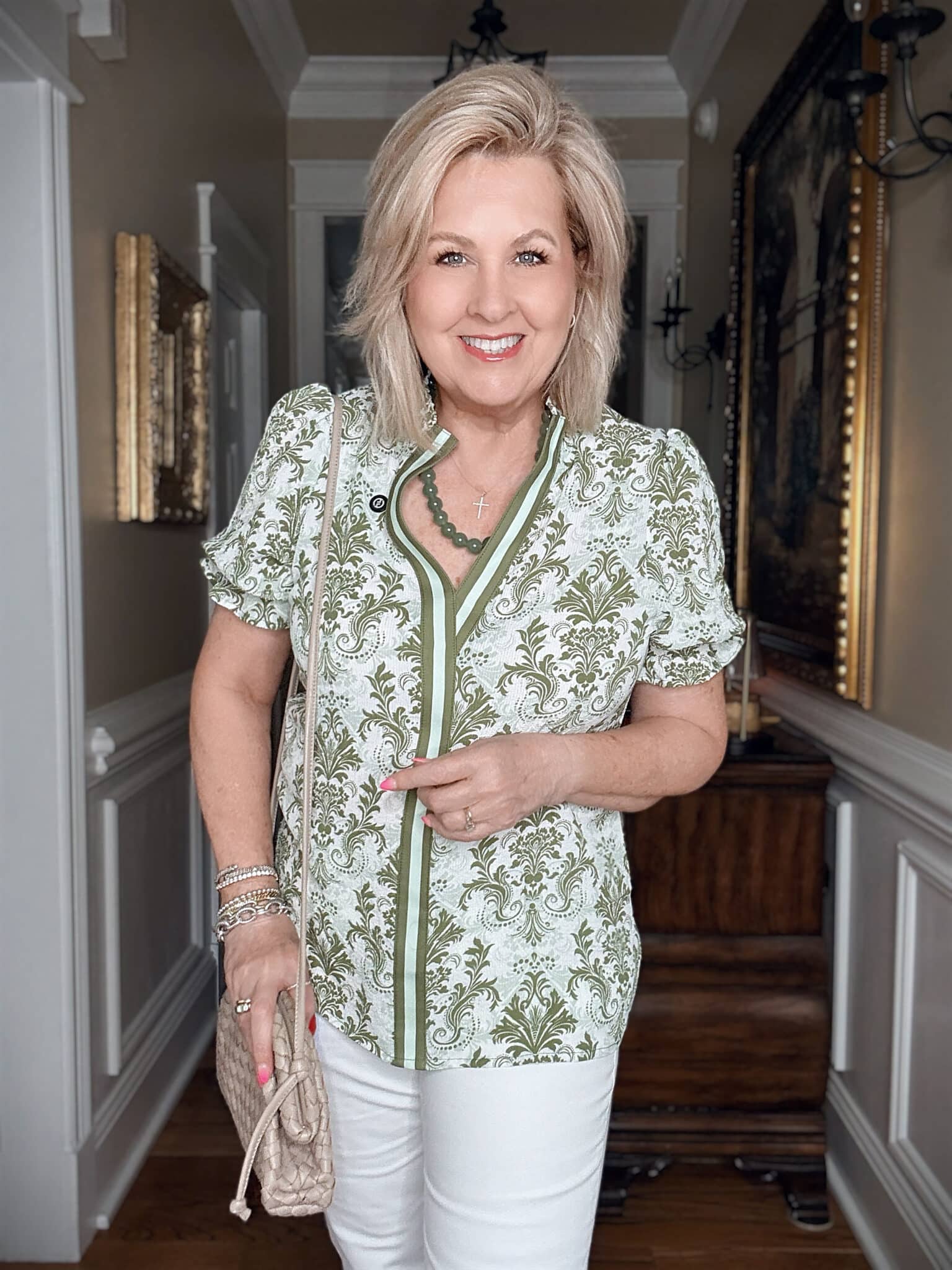Tania wearing a green and white V-neck top with a bold green necklace
