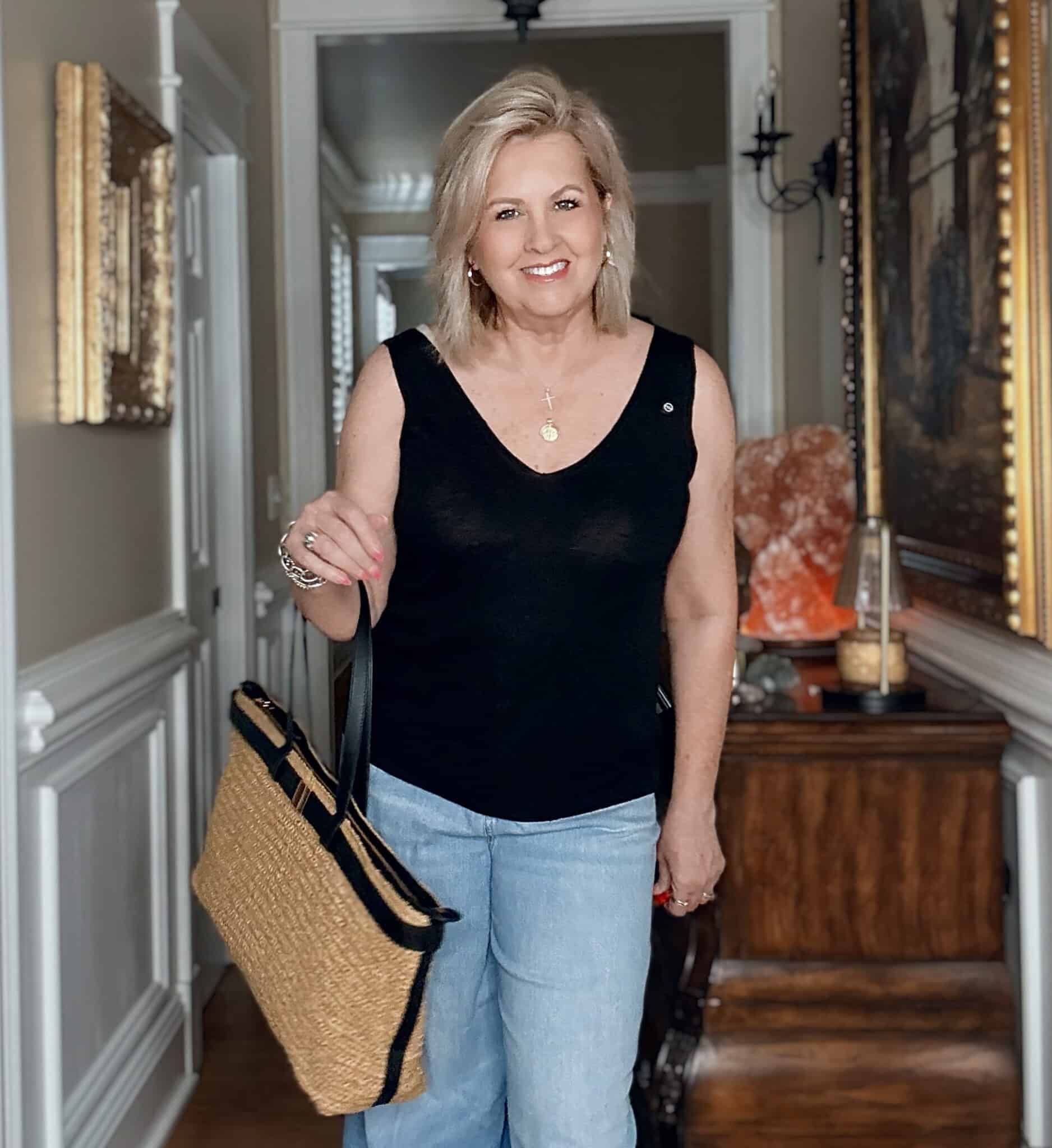 Tania wearing a black linen V-neck tank with a large raffia tote from Apachy
