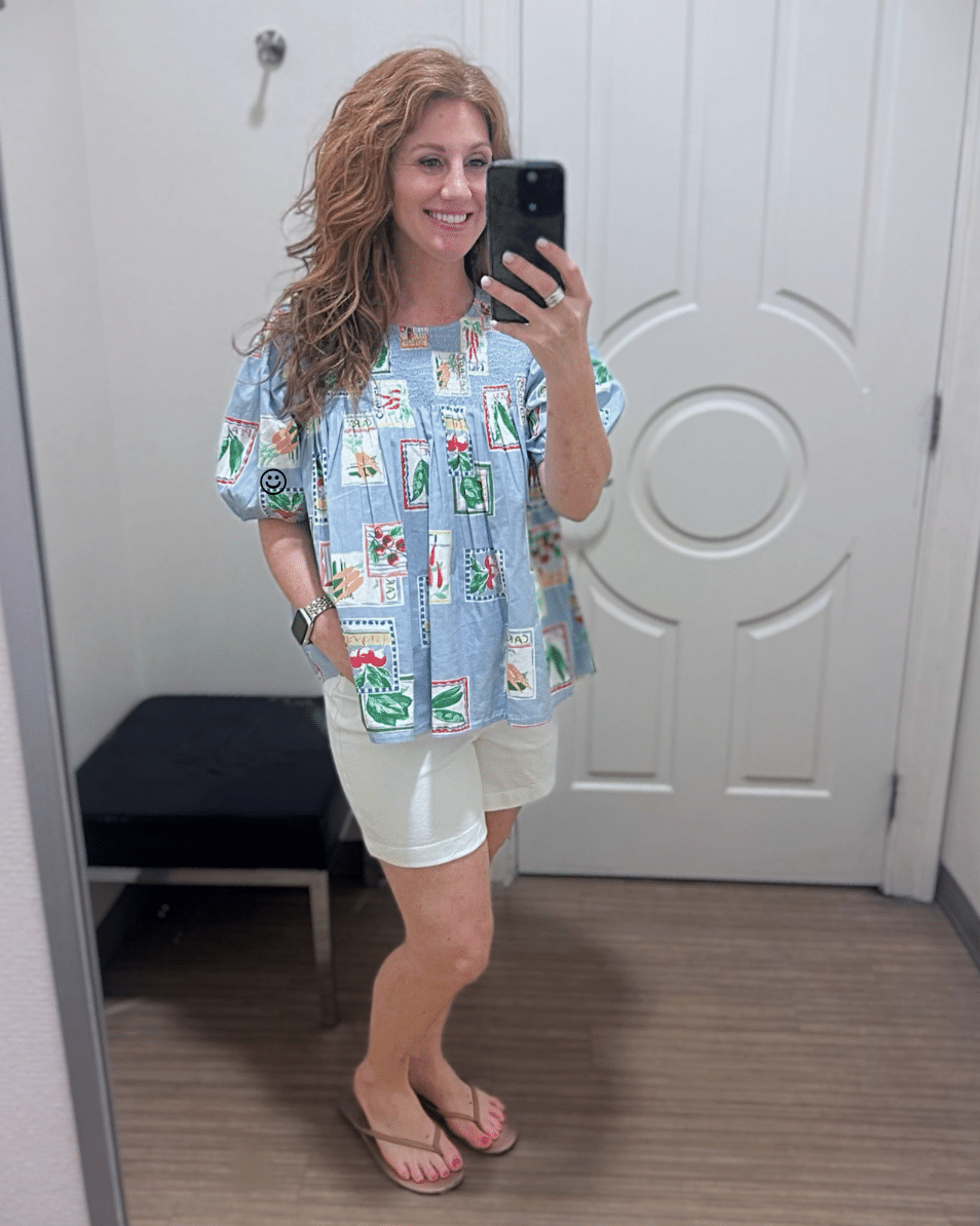 Stephanie wearing a blue printed smocked top with white 7-inch Caroline shorts from Belk.