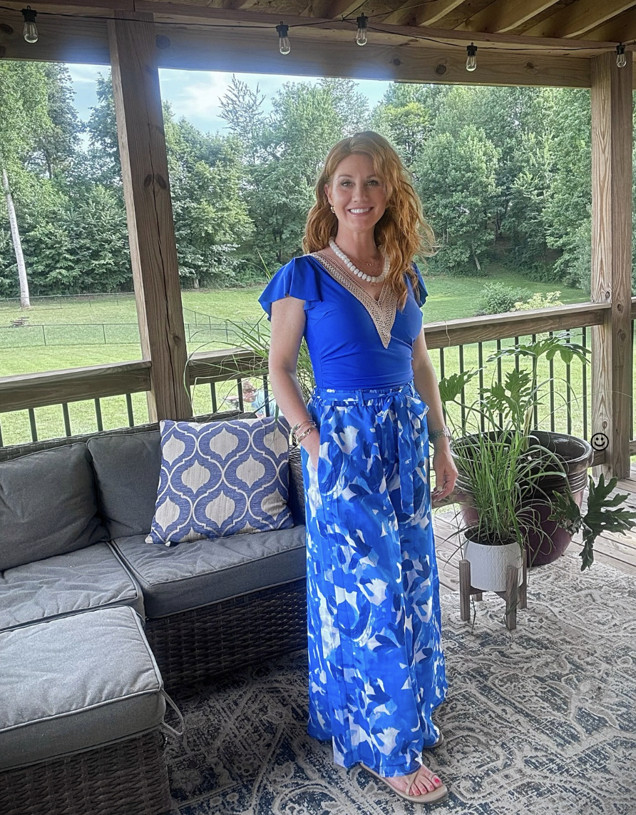 Petite woman wearing a bright blue top with printed wide-leg pants for summer