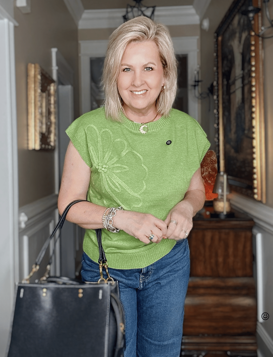 Tania wearing a green embellished sweater with a leather black tote
