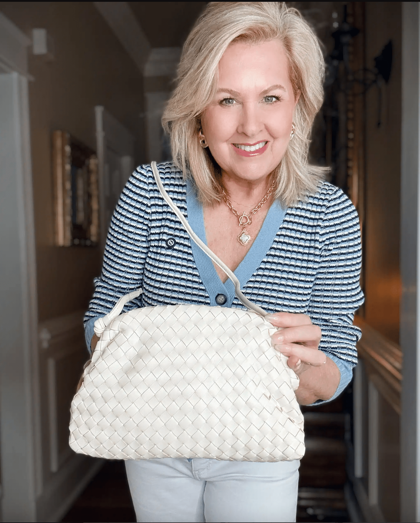 Tania wearing a striped cardigan with an ivory woven handbag from Quince