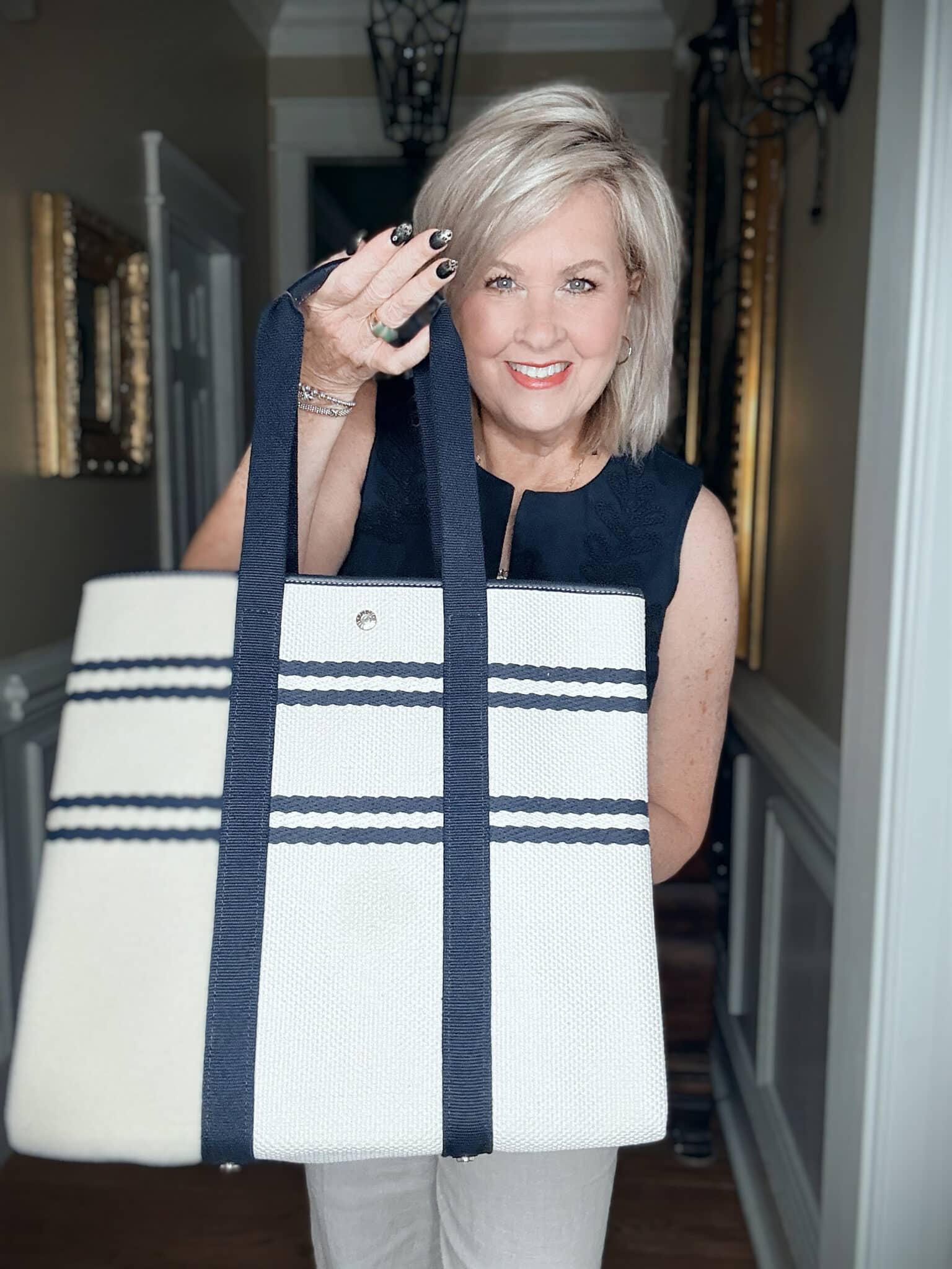 Tania wearing a navy eyelet top with a navy & white handbag
