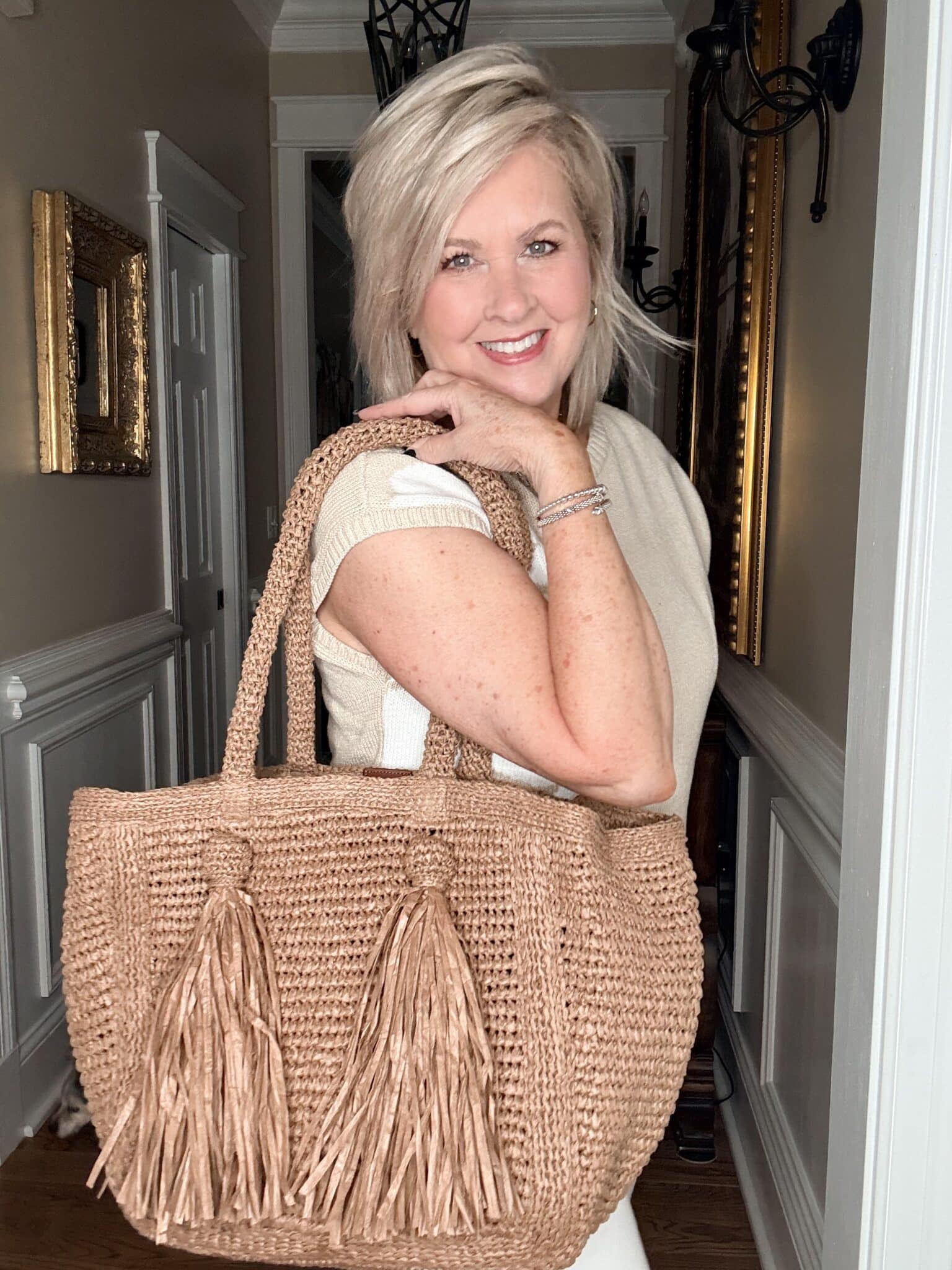 Tania wearing a neutral floral sweater with a large tassel raffia tote from J.Jill