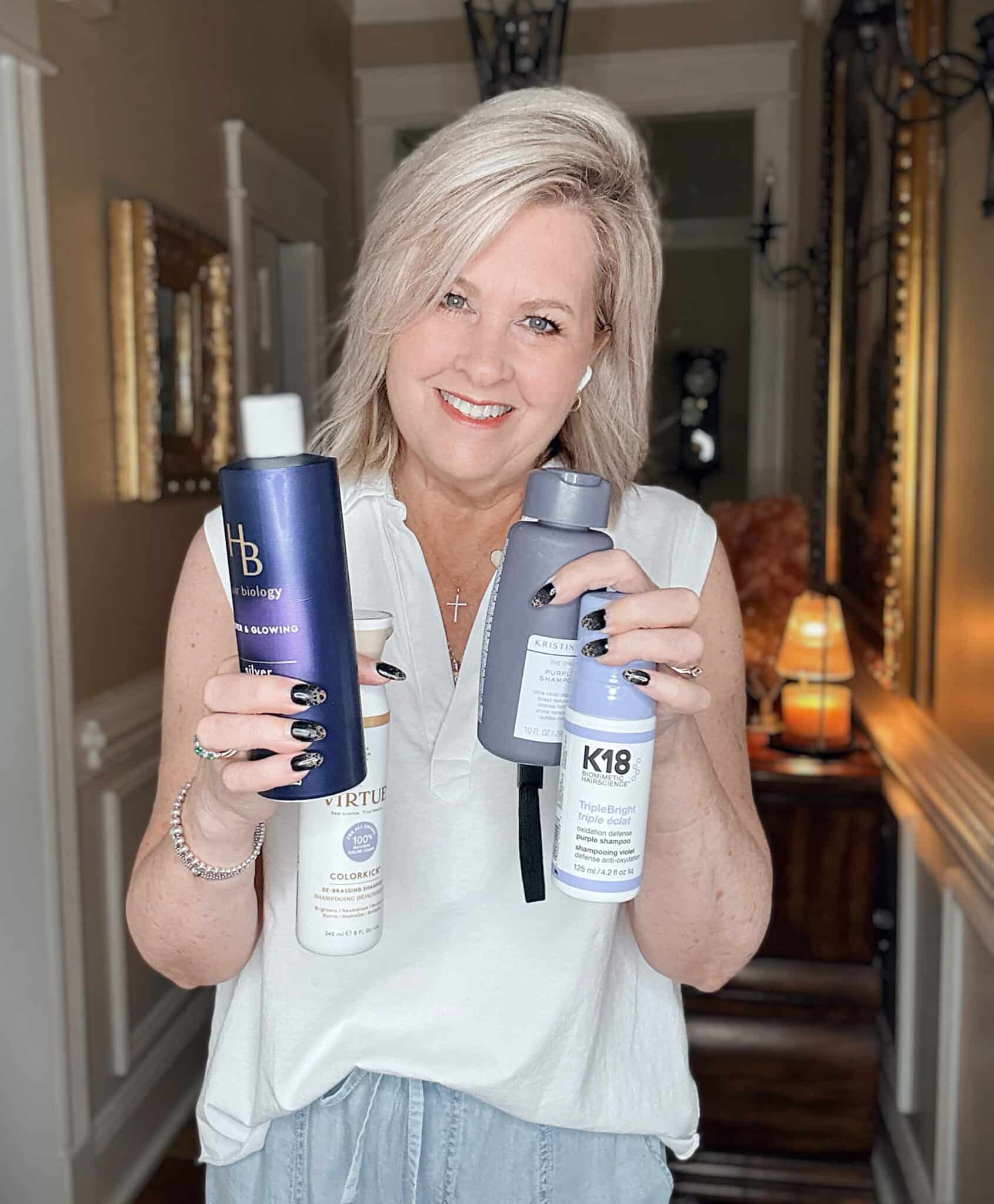 Tania holding the four purple shampoos for gray and blonde hair that she uses