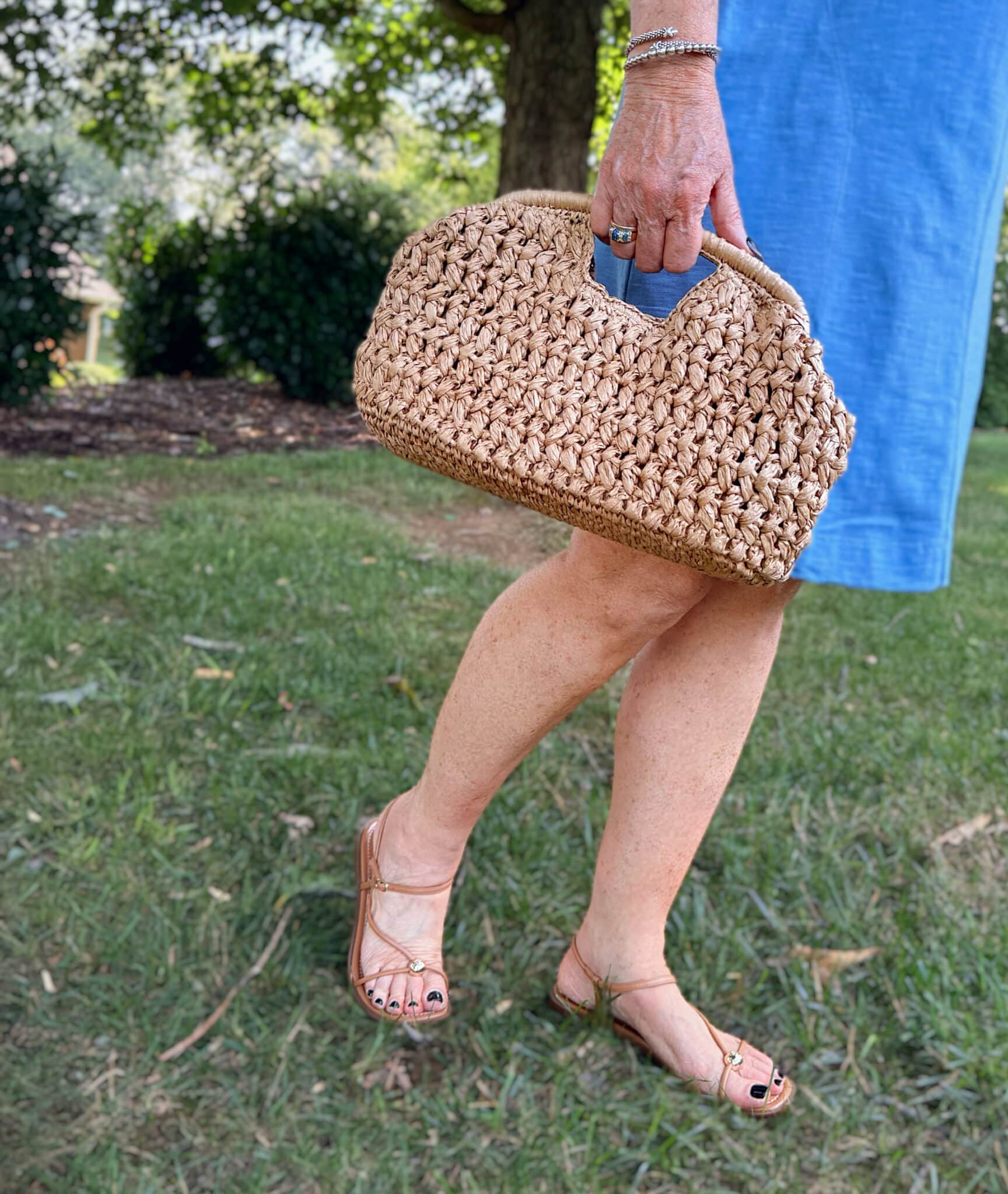 Tania holding a raffia clutch and wearing strappy sandals