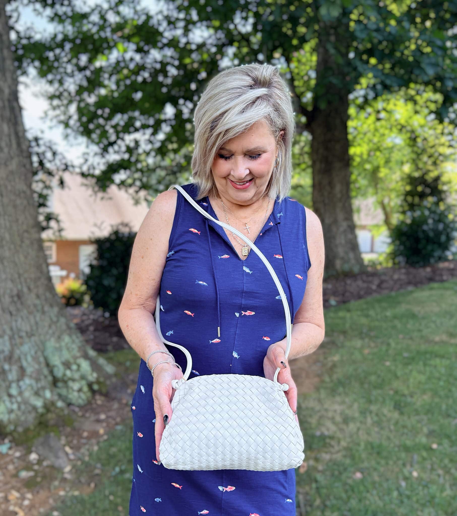 Tania wearing a fish printed dress with a woven crossbody from Quince