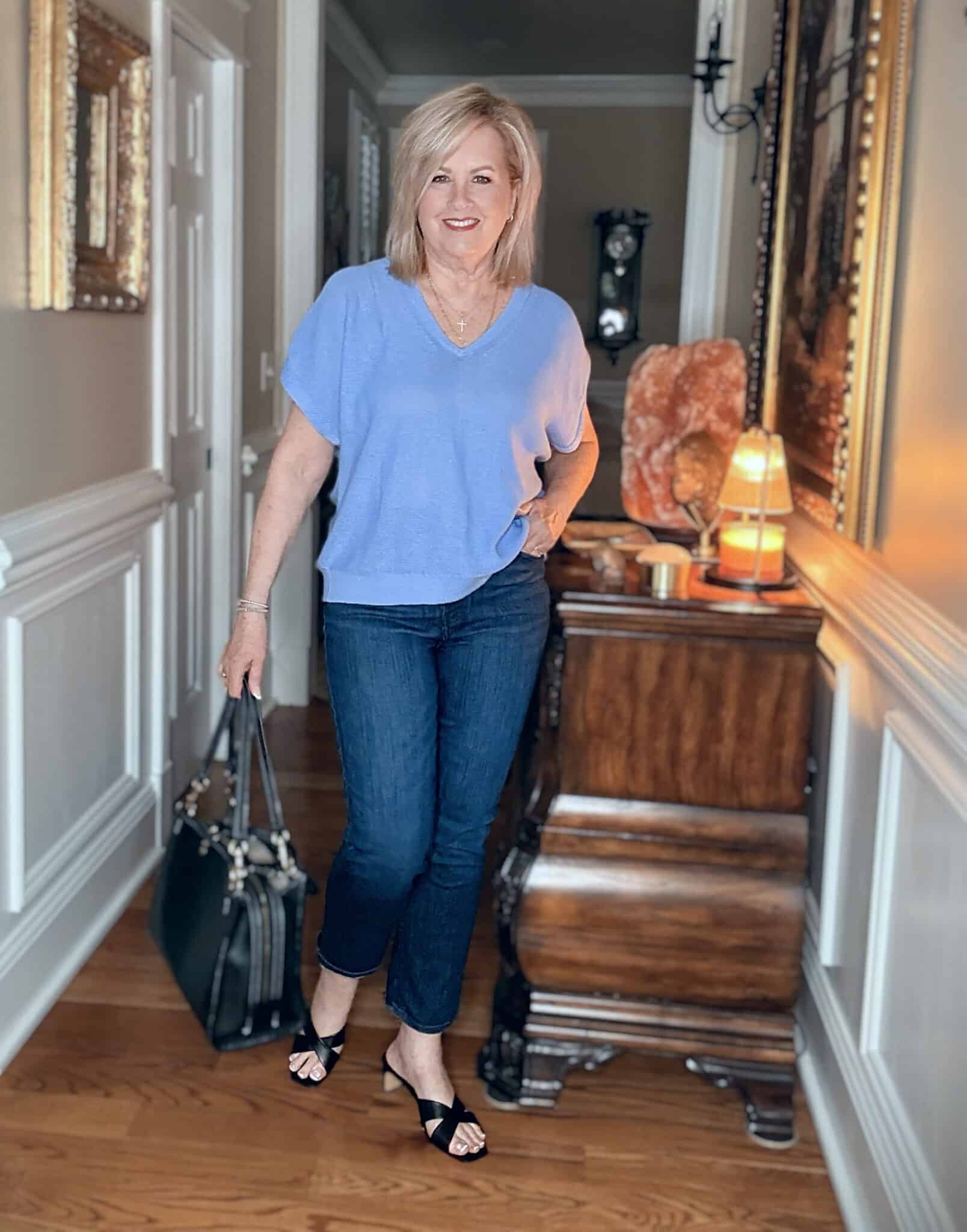Tania wearing a blue v-neck sweater with dark wash crop jeans