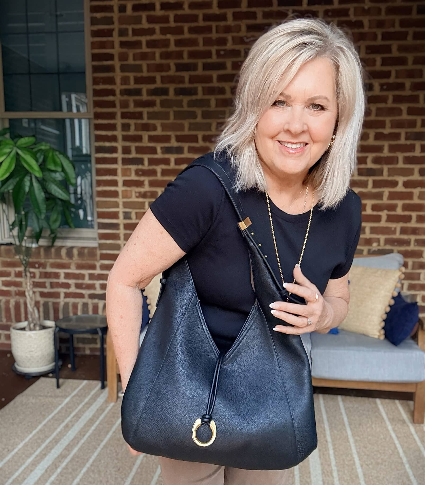 Tania holding a black leather hobo style handbag by Dolce Vita