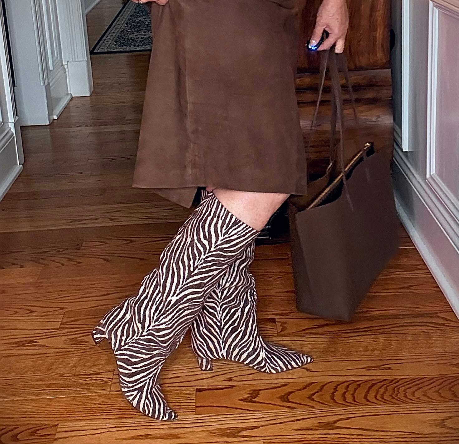 Tania wearing a brown cashmere sweater with a suede midi skirt with Zebra/Tiger print knee boots