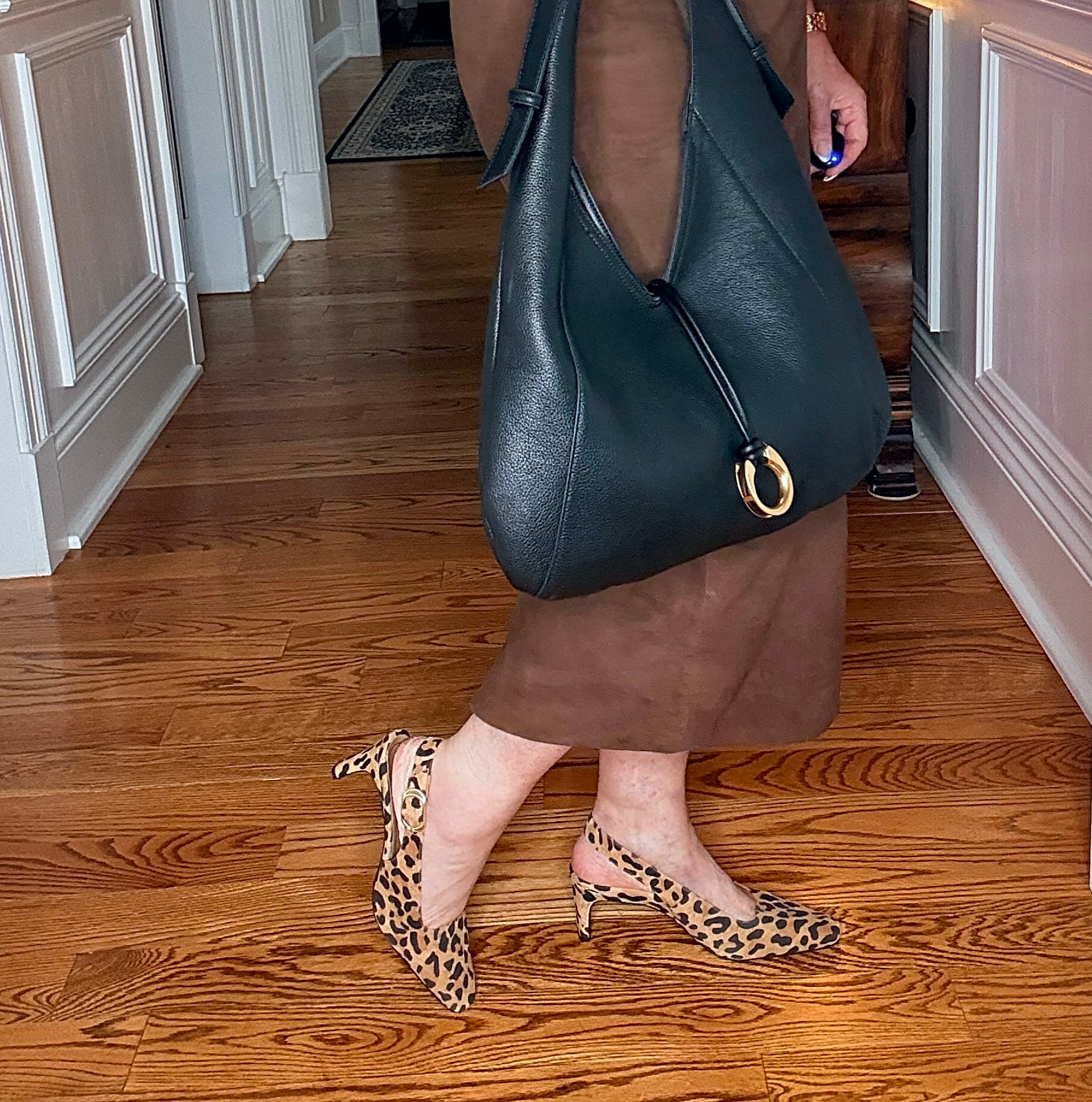 Tania wearing a black t-shirt with a suede midi skirt with leopard print slingback shoes