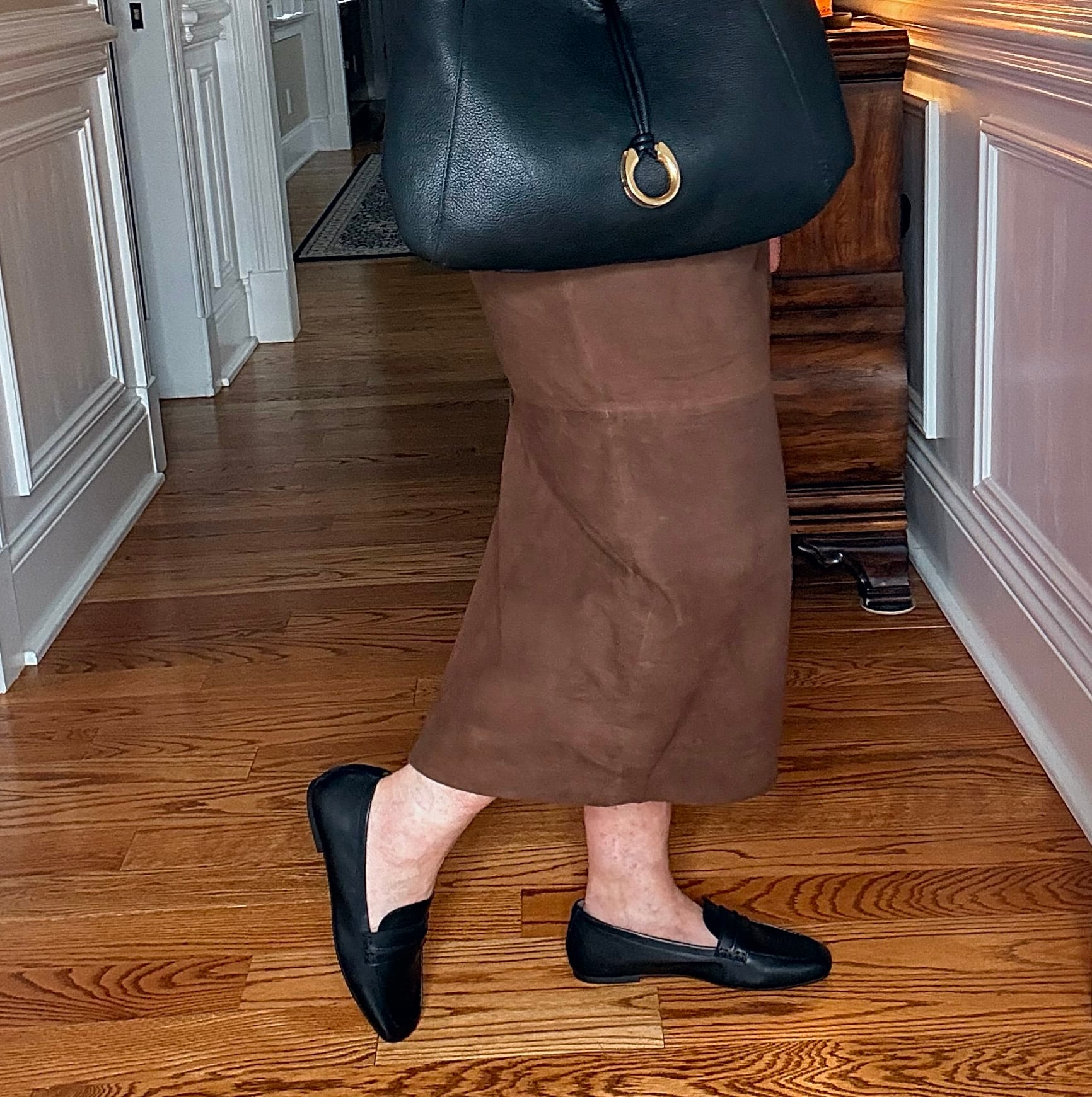 Tania wearing a black t-shirt with a suede midi skirt with Vionic black loafers
