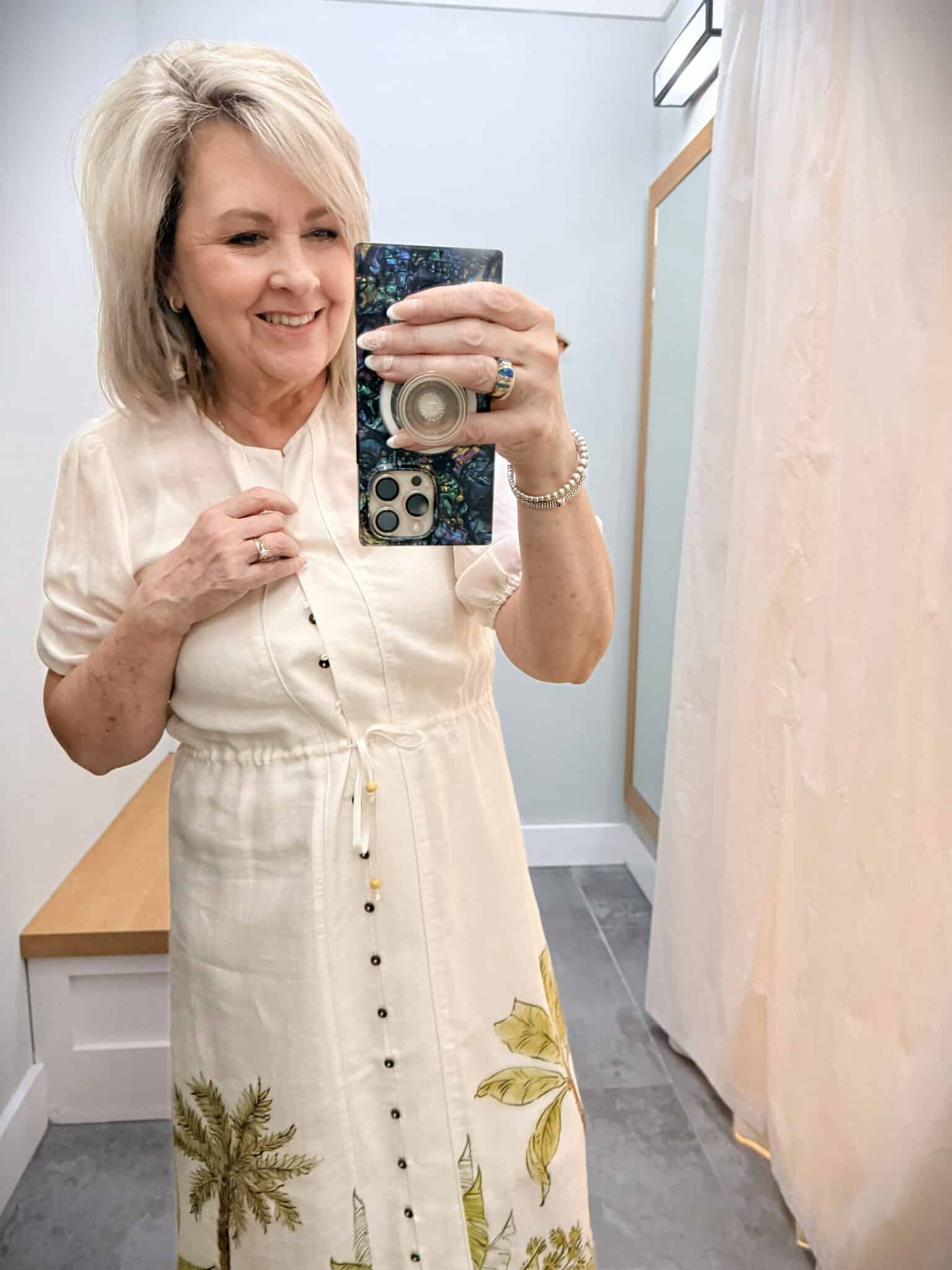 Tania showing the buttons of a Linen shirtdress with a palm tree print at the hem