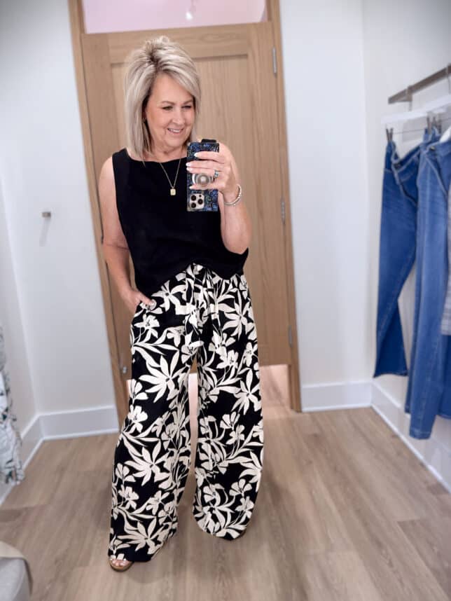 Tania wearing a black sleeveless shirt with floral wide leg pants from Ann Taylor