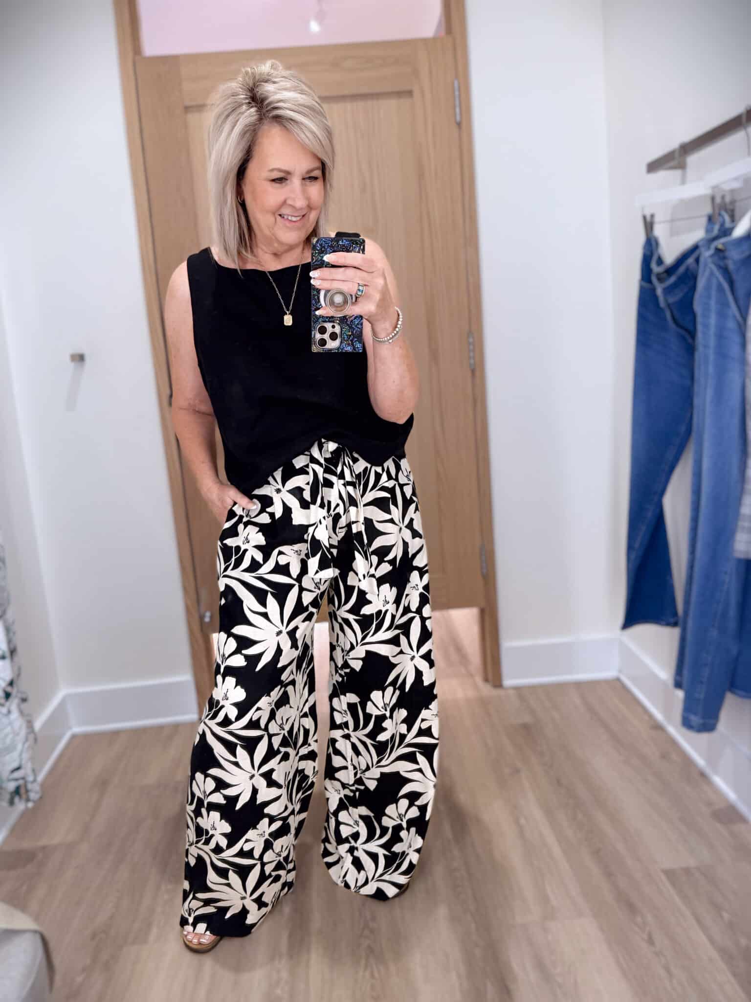 Tania wearing a black sleeveless shirt with floral wide leg pants from Ann Taylor